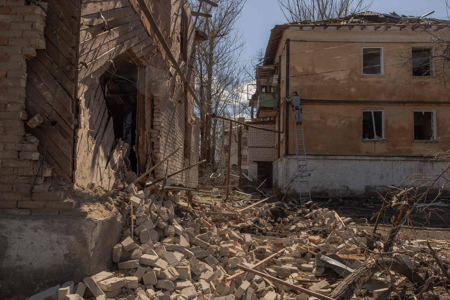 Un hombre realiza trabajos de reparación junto a edificios residenciales dañados por un bombardeo este sábado, en la ciudad de Mykolaivka, cerca de Slaviansk, en el norte de la región de Donetsk, al este de Ucrania, en medio de la invasión rusa de Ucrania. (Foto de Román PILIPEY / AFP)