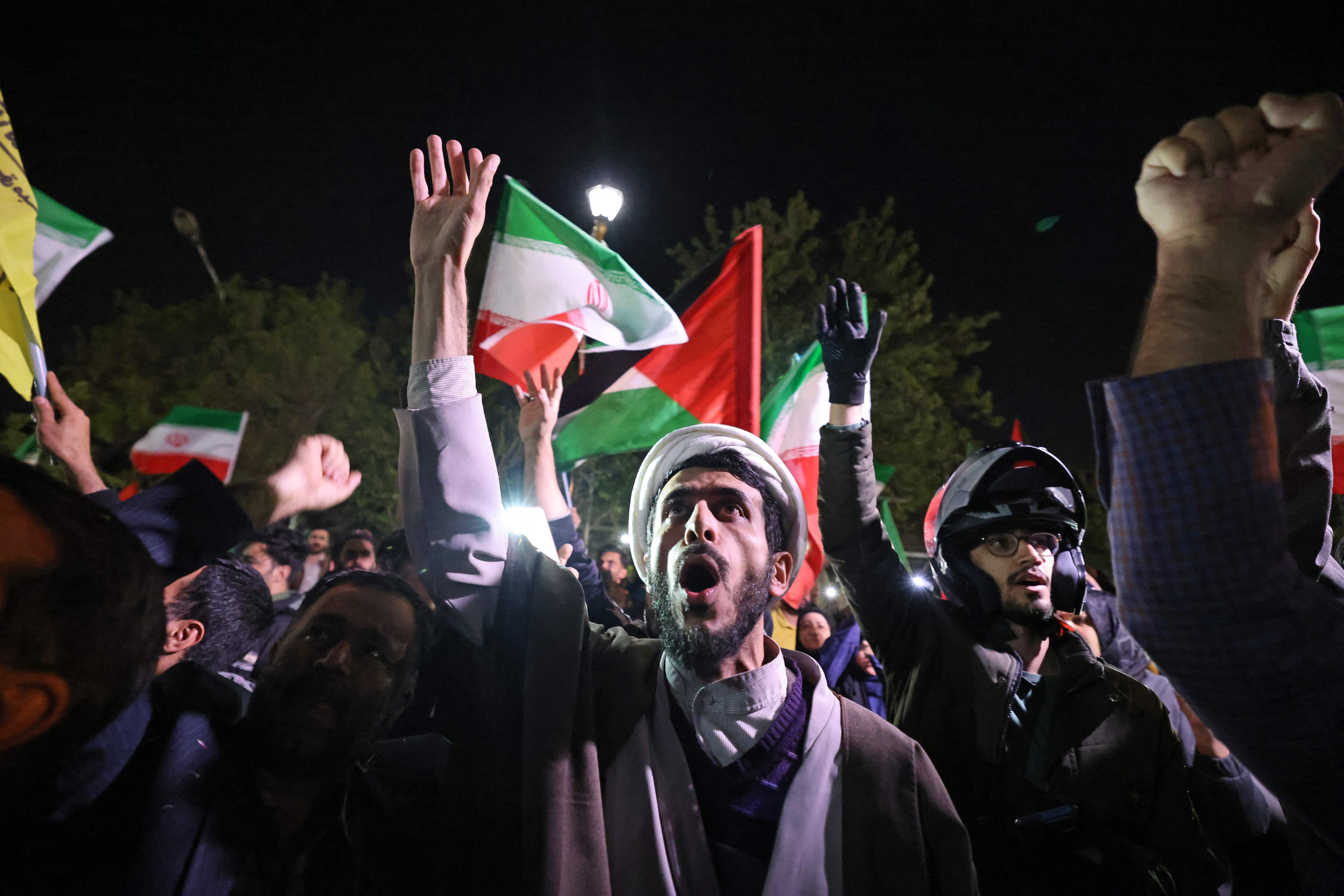 Los manifestantes ondean la bandera de Irán y las banderas palestinas mientras se reúnen frente a la embajada británica en Teherán ayer 14 de abril de 2024, después del ataque con aviones no tripulados y misiles contra Israel.