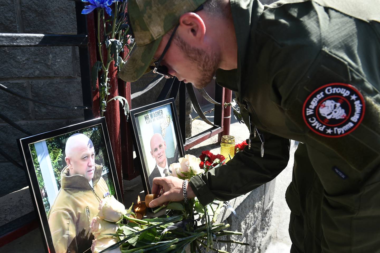 Un miembro del grupo mercenario privado Wagner rinde homenaje a Yevgeny Prigozhin (izq.) y Dmitry Utkin, una figura oscura que dirigió las operaciones de Wagner y supuestamente sirvió en la inteligencia militar rusa, en el memorial improvisado frente a la oficina de PMC Wagner en Novosibirsk