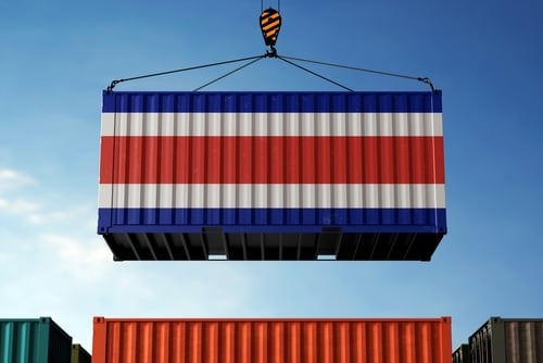 Contenedor con la bandera de Costa Rica siendo levantado por una grúa en un puerto, simbolizando comercio internacional y acuerdos económicos.