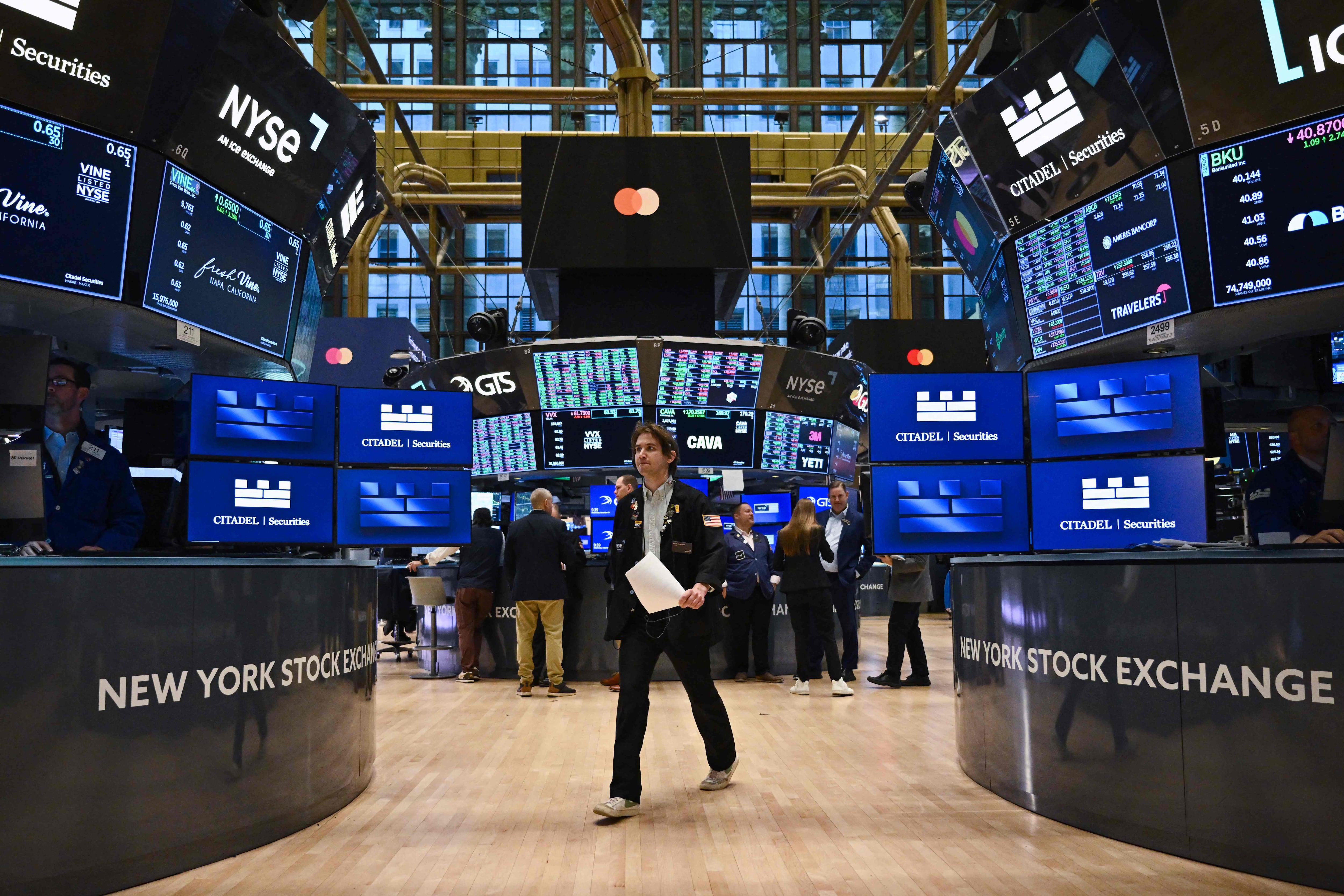 ala de operaciones de la Bolsa de Nueva York con pantallas mostrando caídas en los índices bursátiles tras el anuncio de la Reserva Federal sobre tasas de interés.