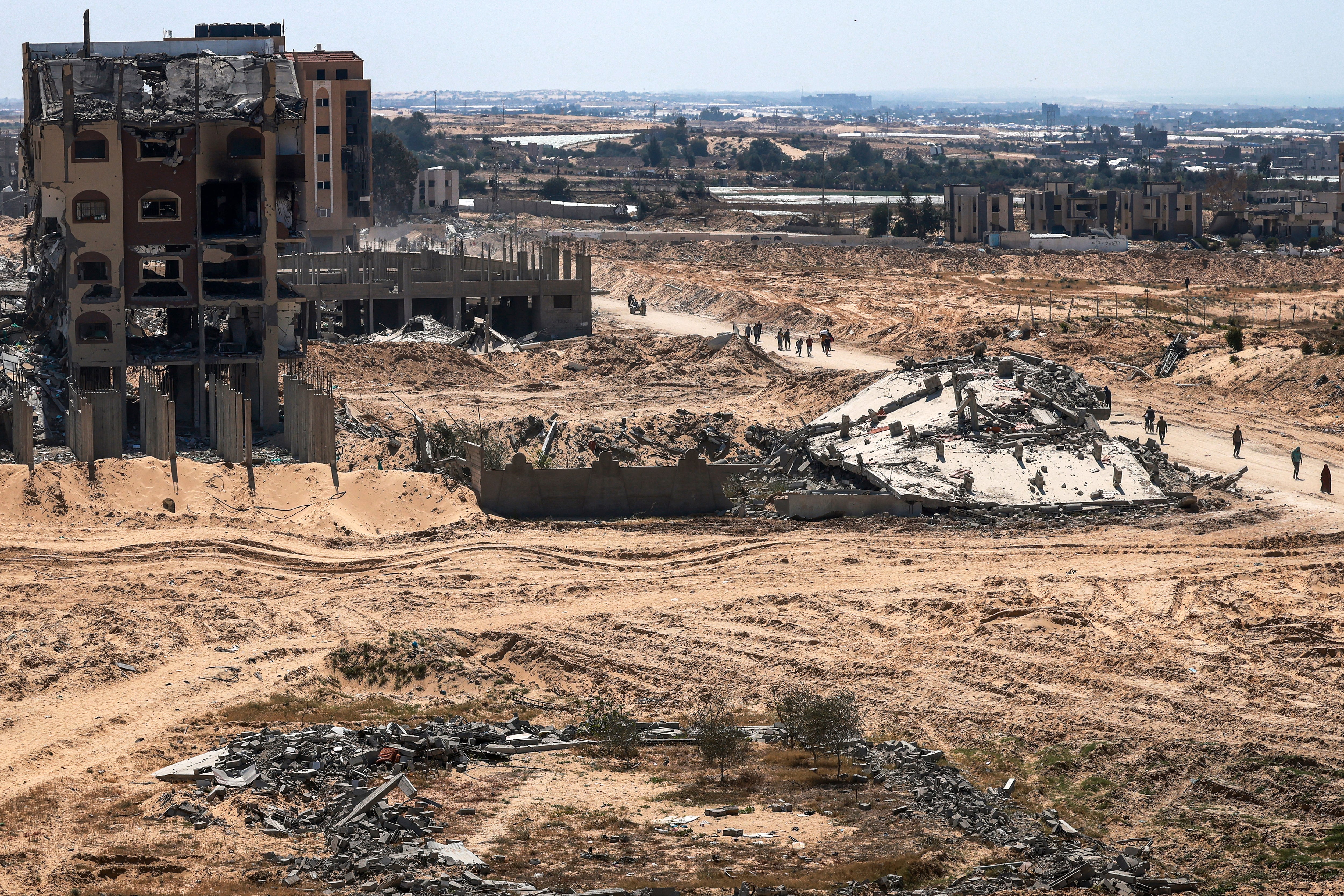 La gente pasa junto a edificios dañados y destruidos en Khan Yunis.