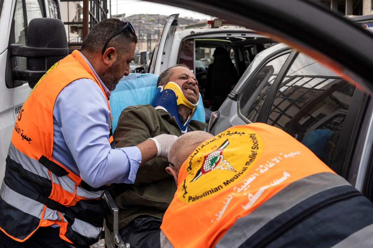 El fotógrafo de la Agence France-Presse (AFP) Jaafar Ashtiyeh es trasladado por socorristas palestinos para recibir atención médica después de ser golpeado por varios israelíes en Aqraba, en la Cisjordania ocupada por Israel, el 6 de octubre de 2026.