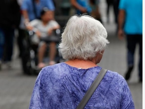 Una adulta mayor camina en la Avenida Central.