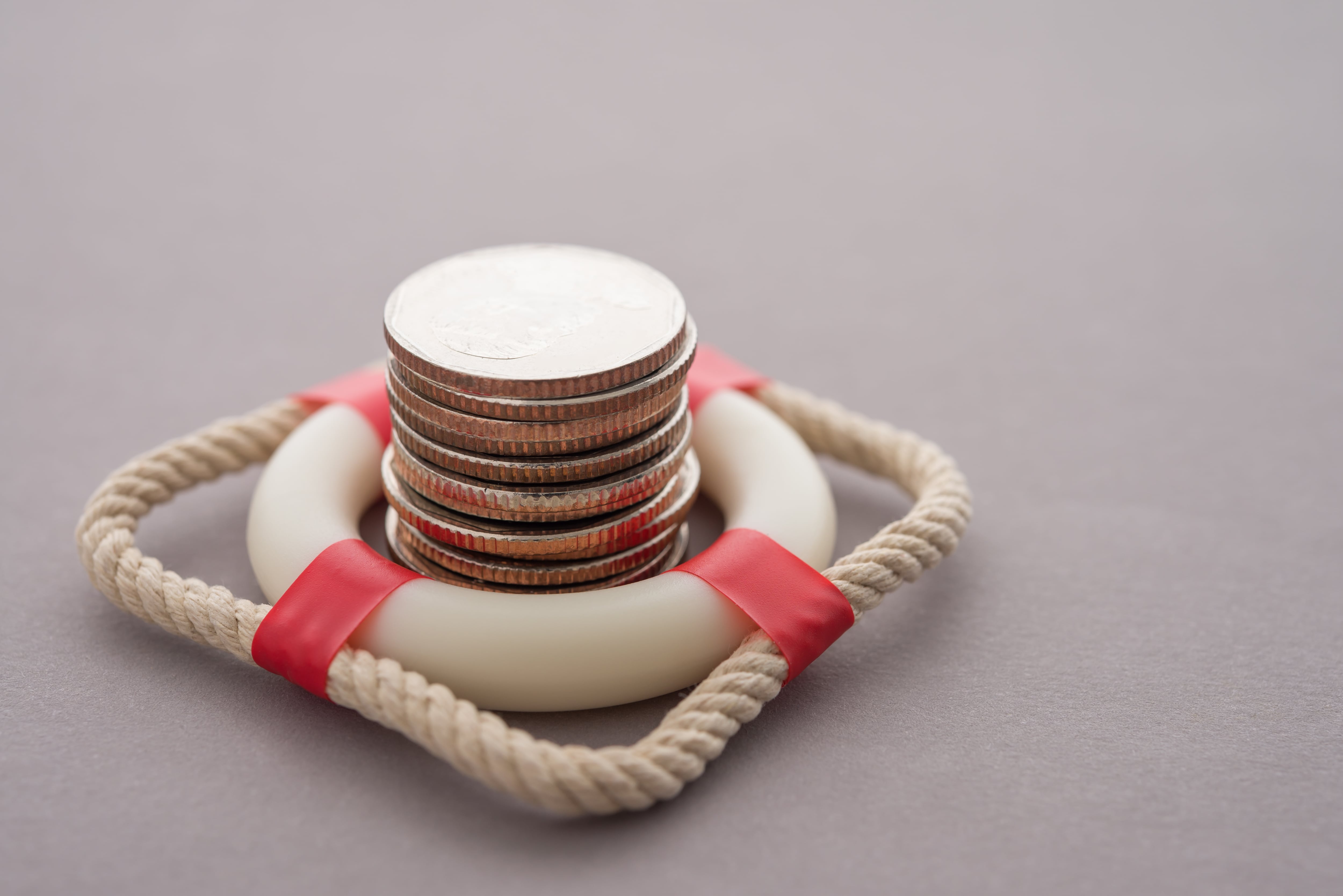Concepto de protección de ahorrante, de los ahorros, salvavidas protege un cerro de monedas