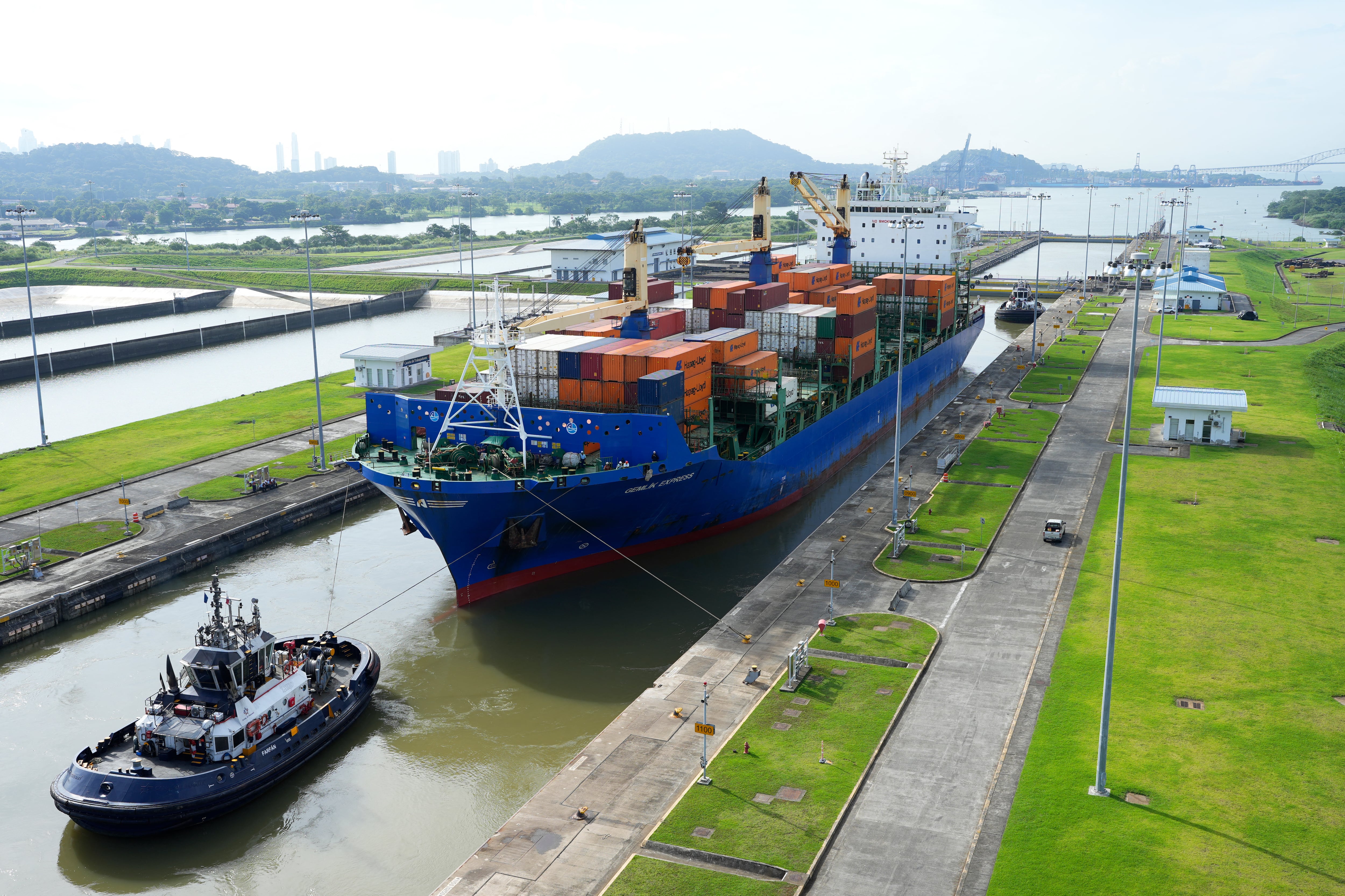 (FILES) A cargo ship and tugboat sail through the Cocoli Locks at the Panama Canal, in Panama, on August 12, 2024. Under fierce pressure from US President Donald Trump, Hong Kong firm Hutchison said it had agreed to sell its lucrative Panama Canal and other ports to a U