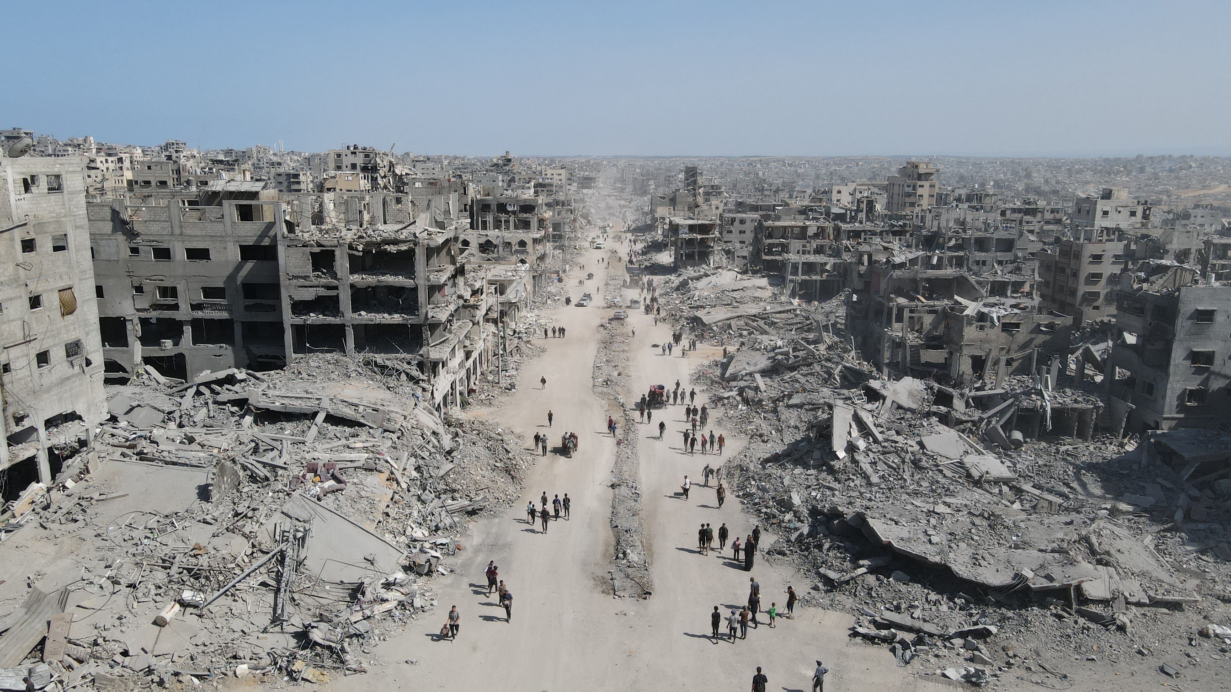 En esta vista aérea, las personas caminan entre la destrucción en la ciudad de Gaza, al norte de la Franja de Gaza, este 11 de octubre, un día después de la entrada en vigor del alto el fuego. Fotografía: