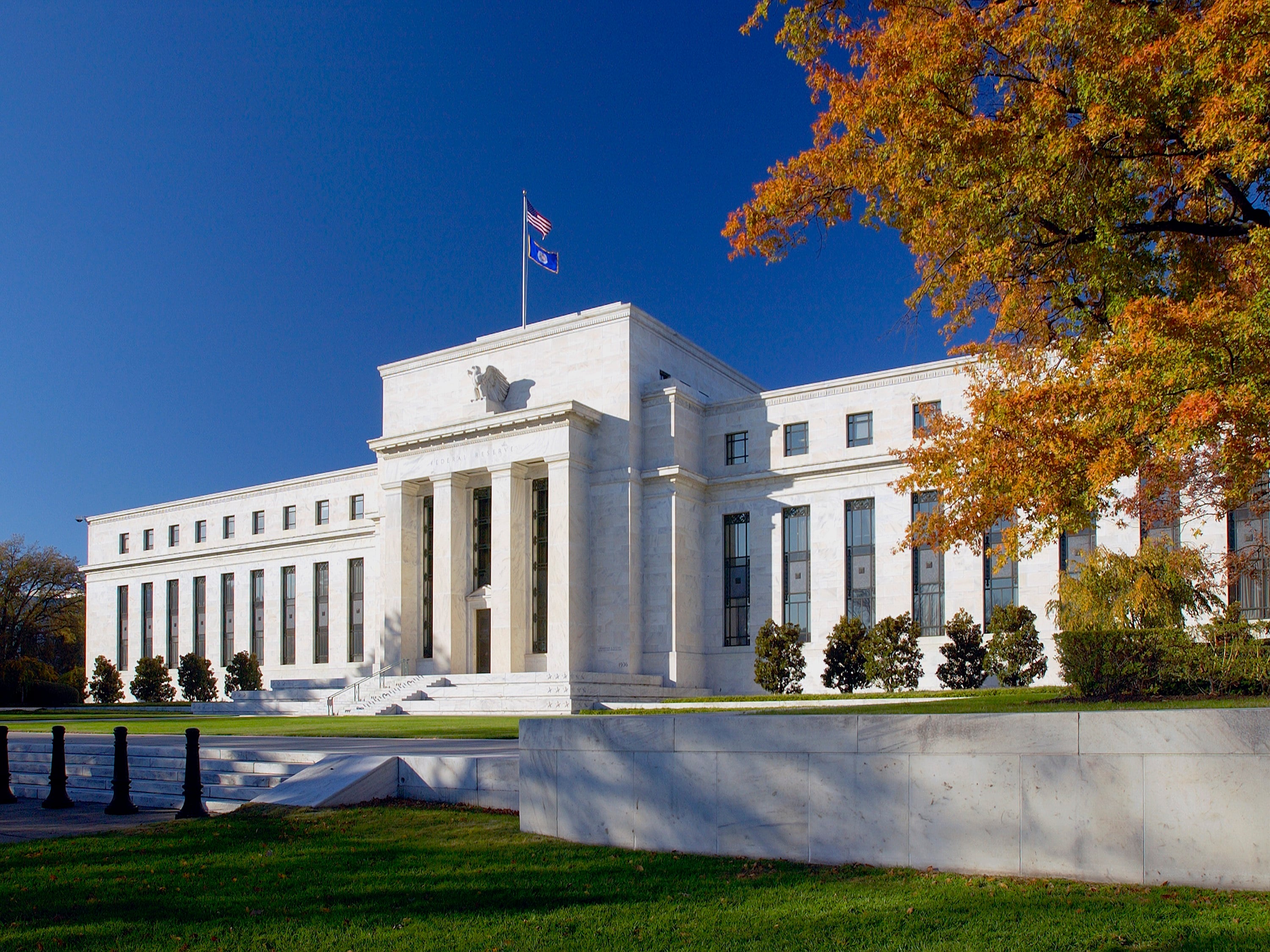 Edificio blanco con columnas y una bandera, sede de la FED, ubicado en Washington D.C.