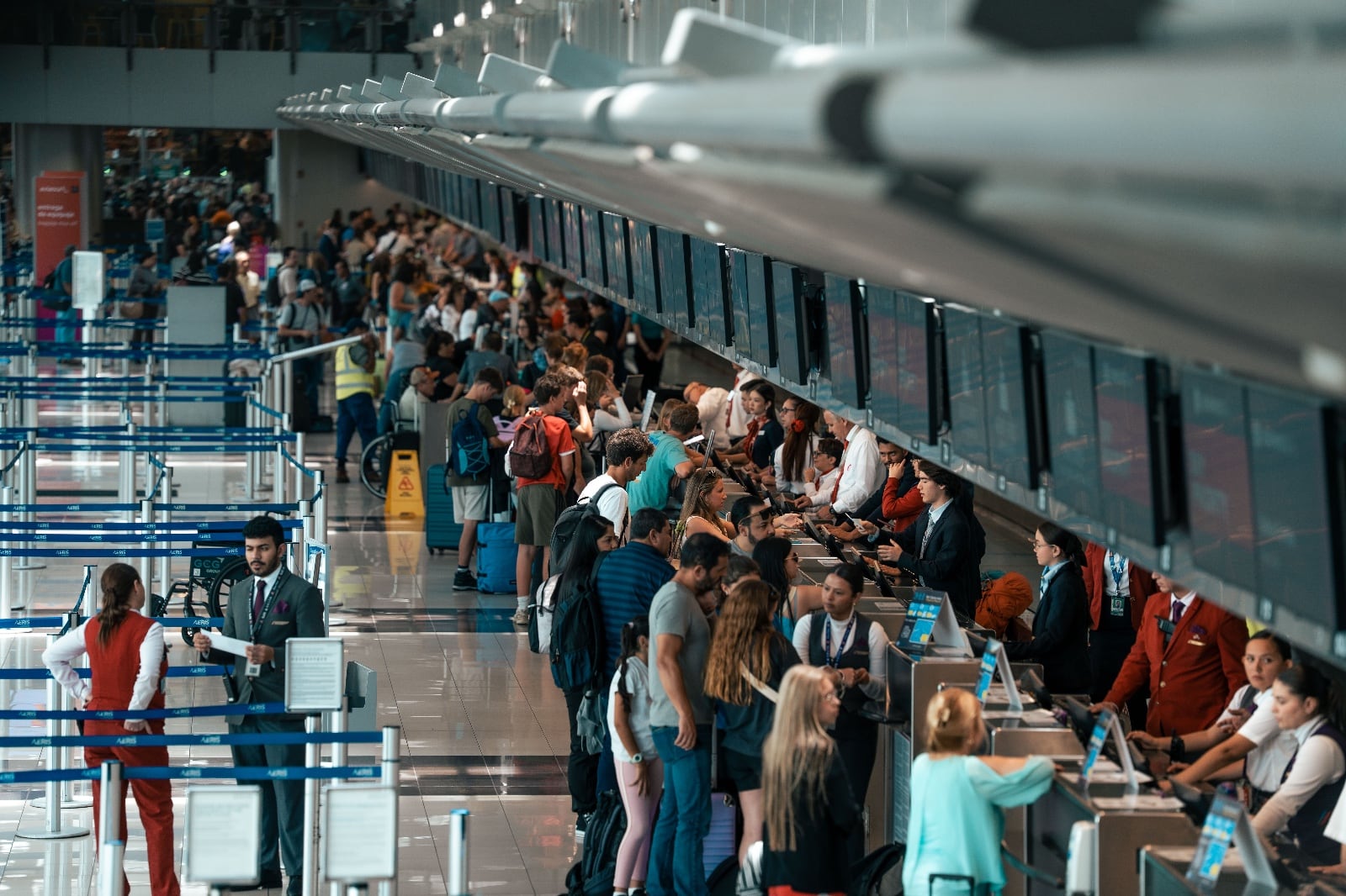 Pasajeros realizando el proceso de registro en los counters del Aeropuerto Internacional Juan Santamaría durante la temporada alta de turismo en Costa Rica.