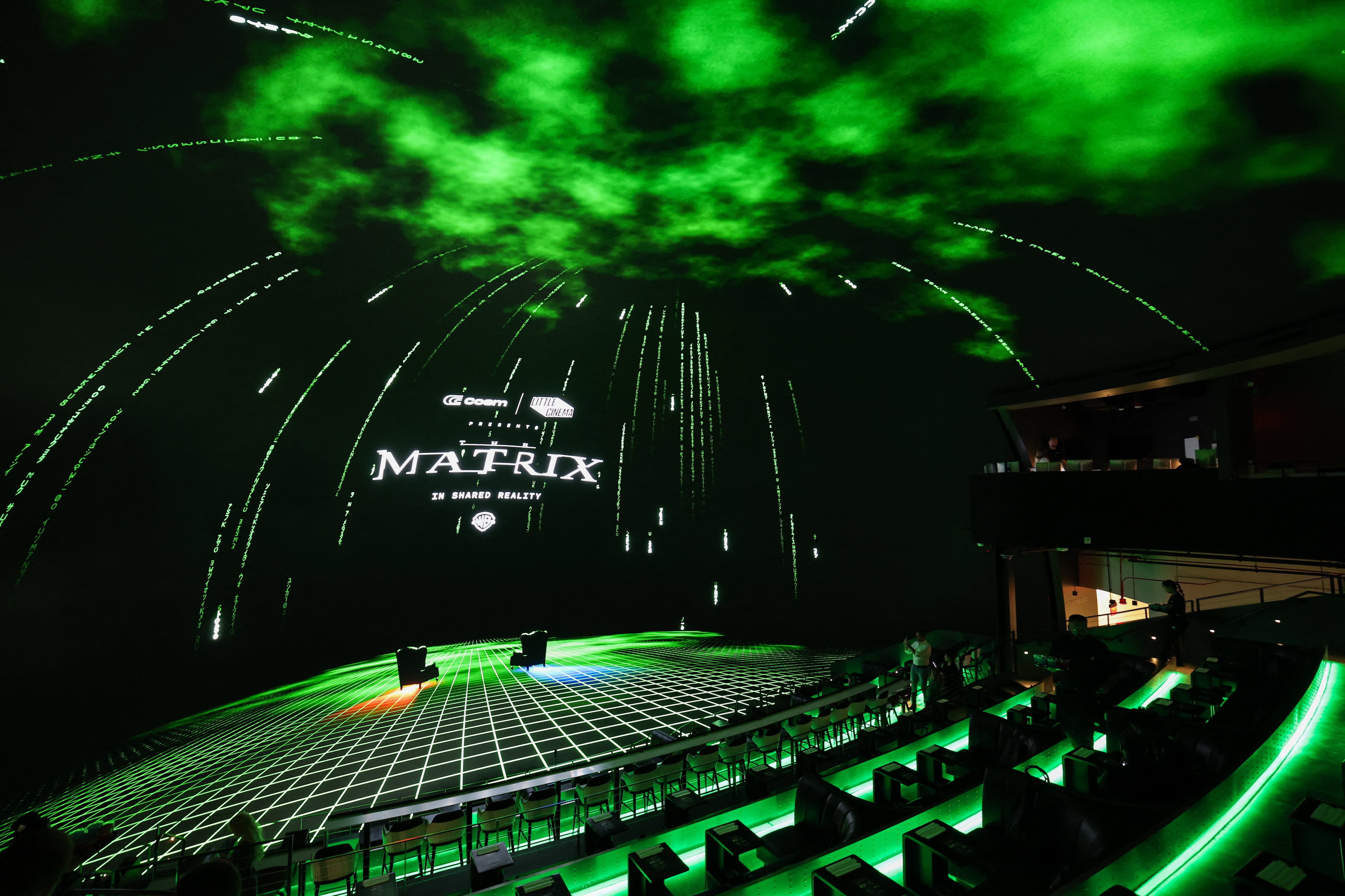 The Matrix logo is displayed before the first shared reality screening of the movie "The Matrix" on an immersive dome screen inside Cosm Los Angeles at Hollywood Park in Inglewood, California on May 28, 2025. A trenchcoat-wearing Neo bends backwards to dodge bullets that spiral over the viewer's head, as the sound of gunfire erupts from everywhere: an industry desperate to bring back audiences is hoping a new immersive experience will be a red pill moment that will get film fans off their couches. That's the bet of the Cosm theater in Los Angeles, whose dome-style screen and 3D sets launch this month (June) with what they are calling a "shared reality' version of "The Matrix," the cult 1999 film starring Keanu Reaves as a man who suddenly learns his world is a fiction. (Photo by Patrick T. Fallon / AFP)