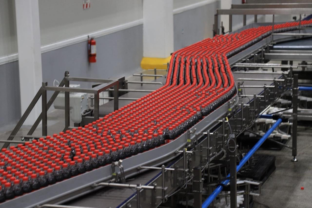 Línea automatizada de embotellado de Coca-Cola FEMSA en Costa Rica con botellas en producción masiva, parte de una inversión para aumentar capacidad, exportaciones y abastecimiento regional.