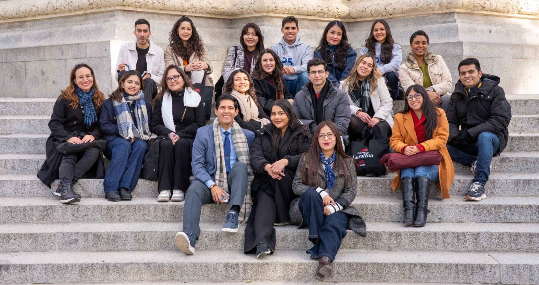 grupo de estudiantes becarios en las escaleras de un monumento en España
