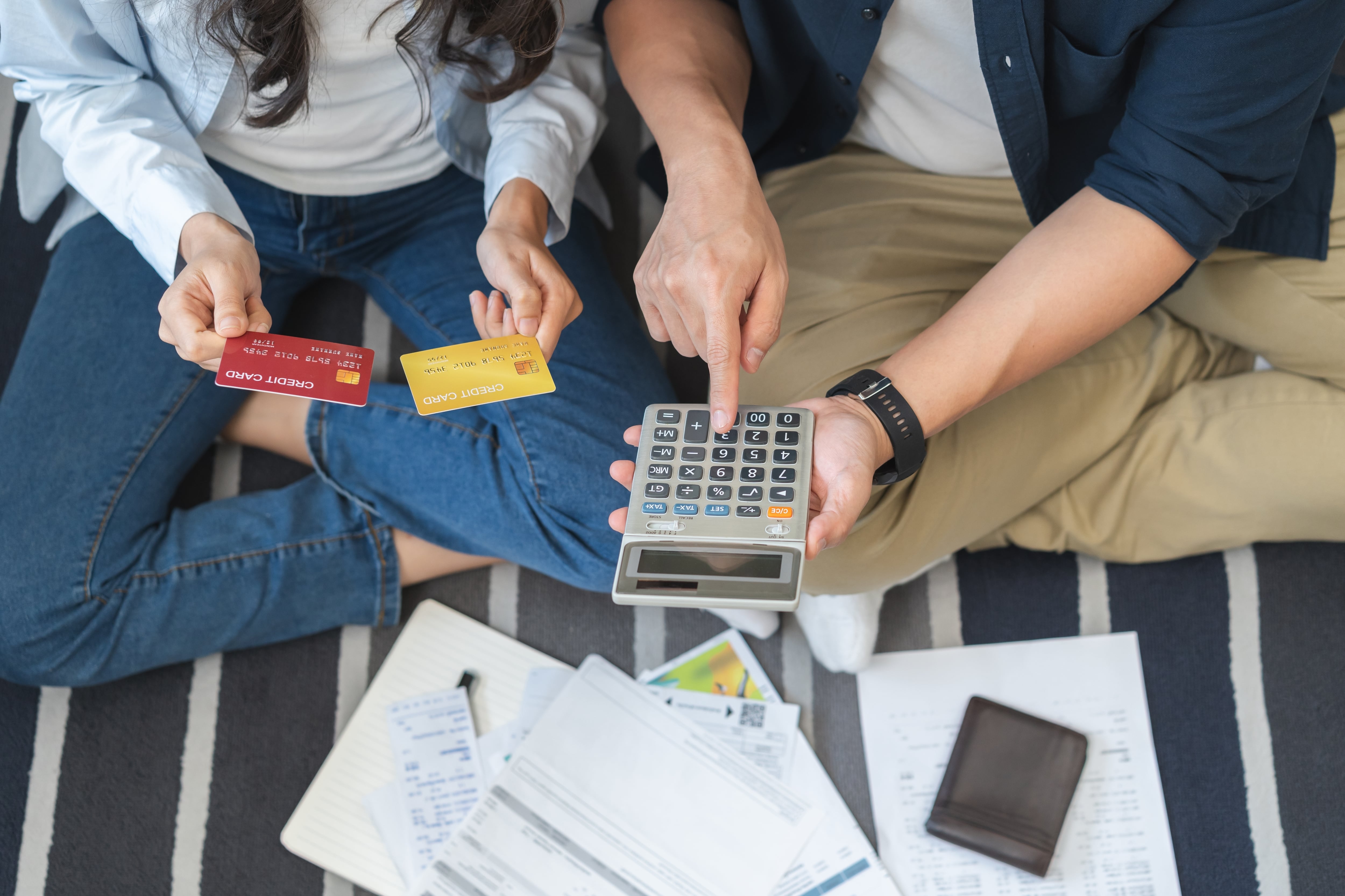 Endeudamiento con tarjetas de crédito, pareja revisa sus estados de cuenta con una calculadora