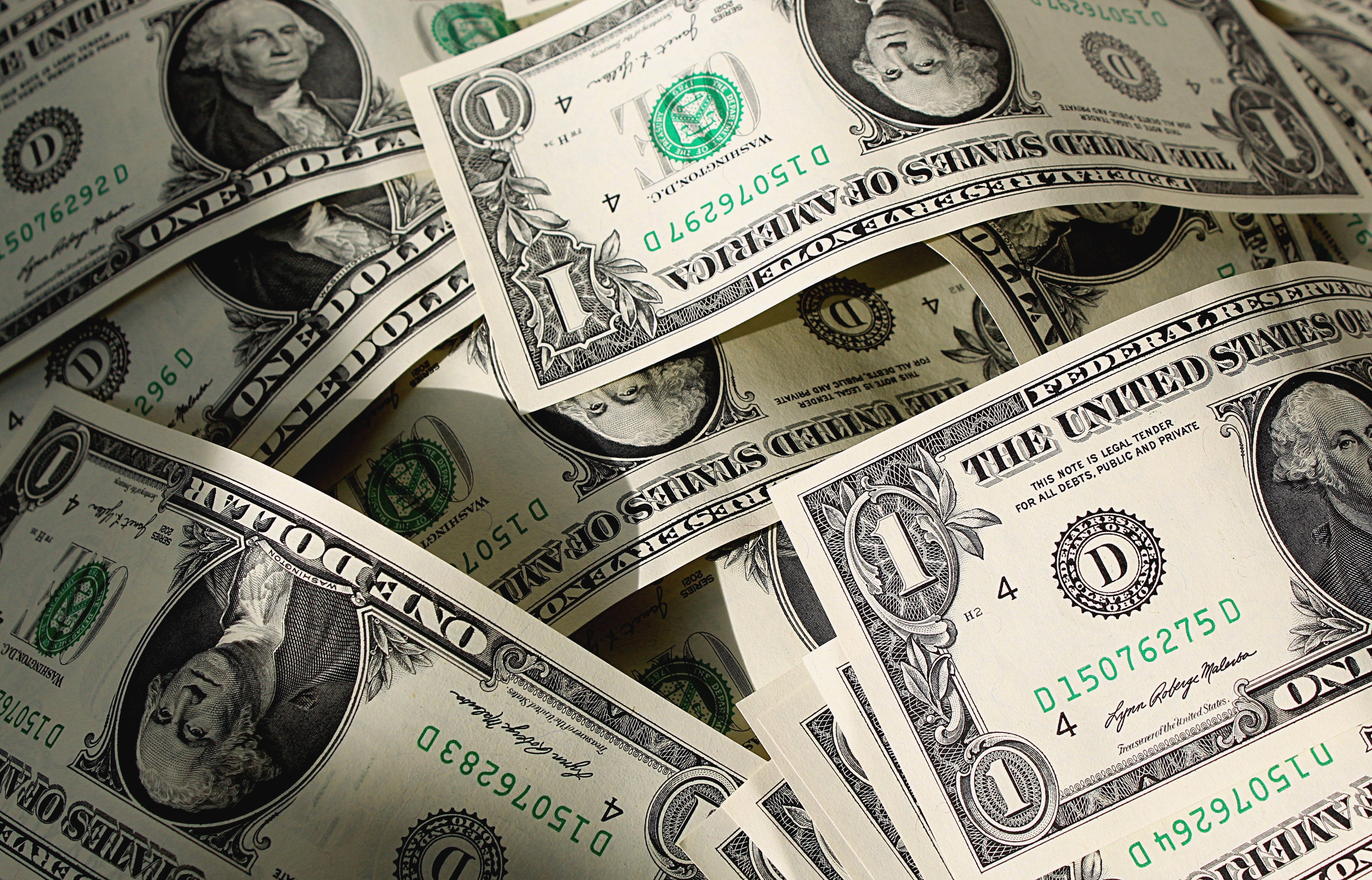 Billetes de dólar estadounidense dispersos, representando el incremento de créditos en dólares en Costa Rica debido a la apreciación del colón y las altas tasas de interés en colones.