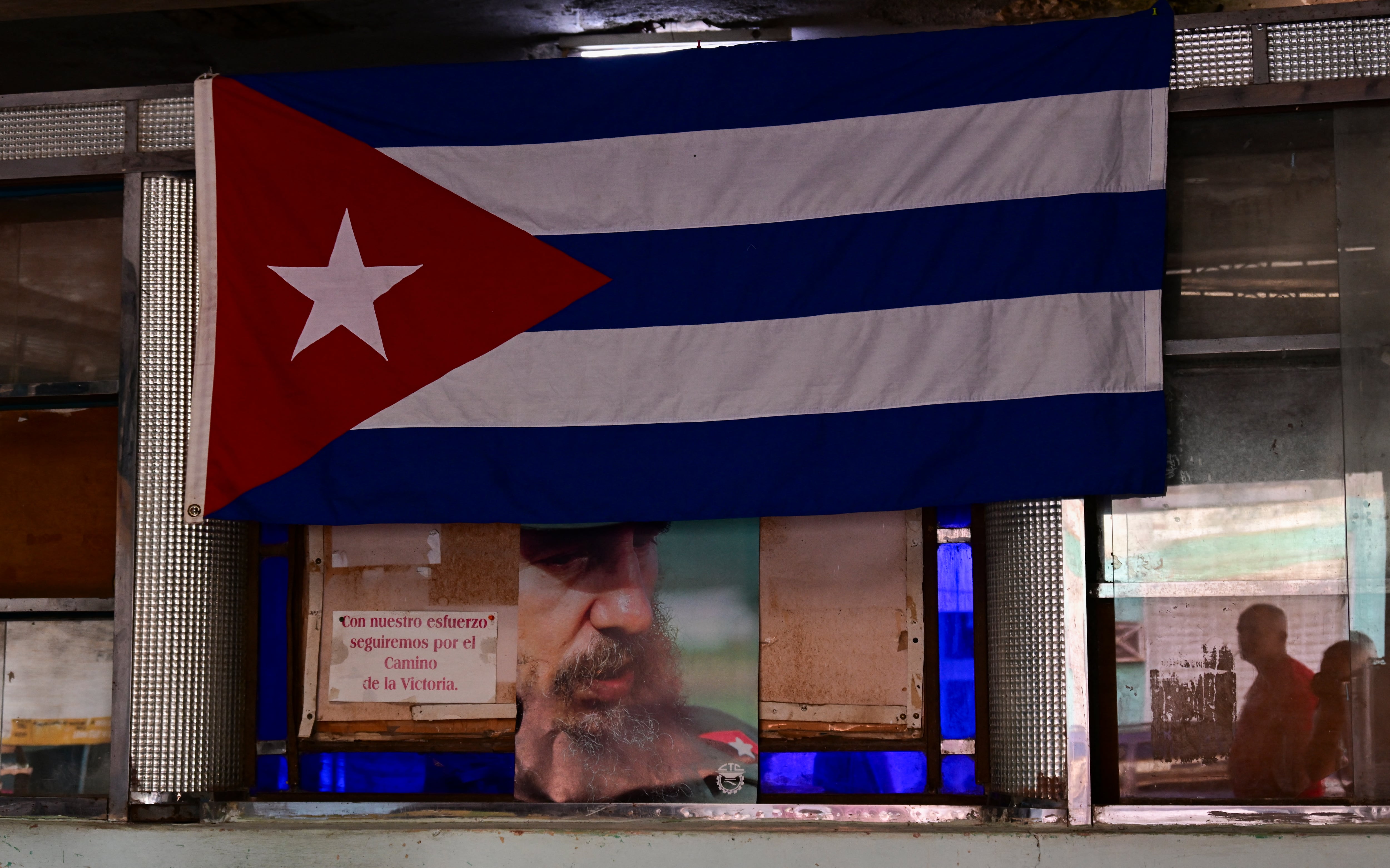 Un retrato del difunto líder cubano Fidel Castro se ve debajo de una bandera cubana dentro de una tienda de racionamiento, conocida localmente como bodega (tienda de comestibles), en La Habana, el 5 de octubre de 2026.
El gobierno de Cuba está sustituyendo las emblemáticas tiendas de racionamiento del país, consideradas durante mucho tiempo uno de los símbolos más visibles del modelo igualitario que caracterizó al socialismo cubano, por nuevos Mercados de Barrio.
