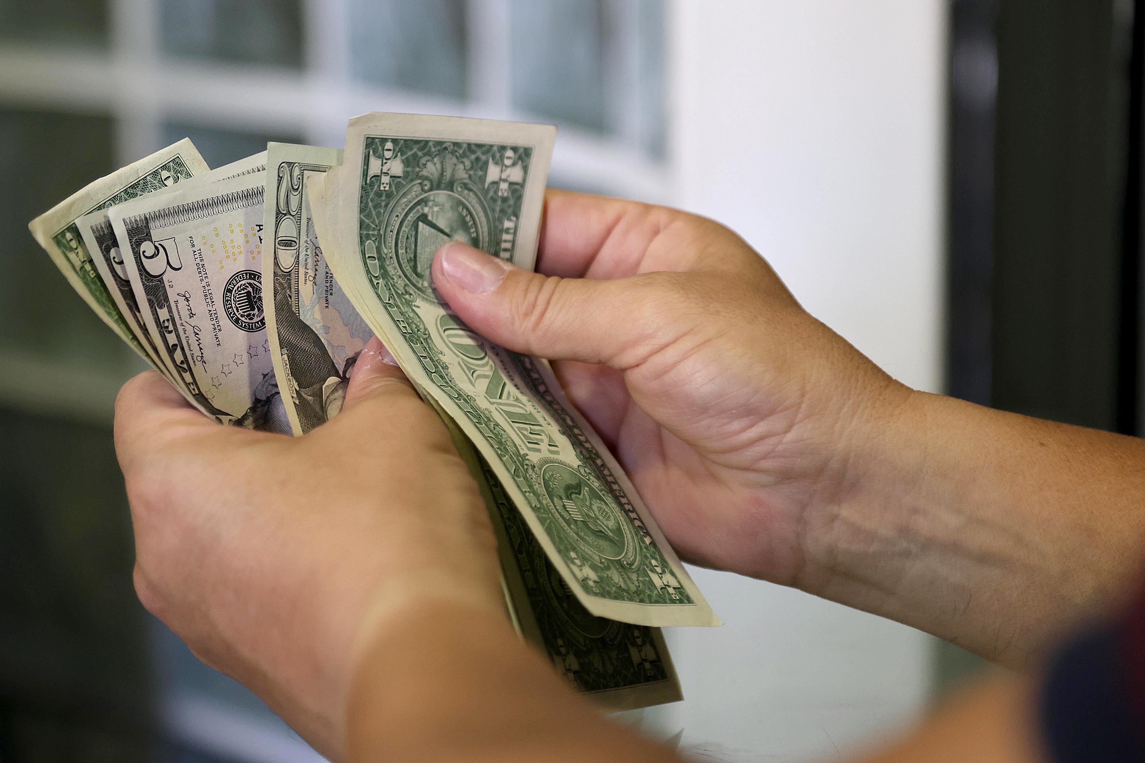 Manos contando billetes de dólar estadounidense, representando el aumento del tipo de cambio en Costa Rica al cierre de 2024.
