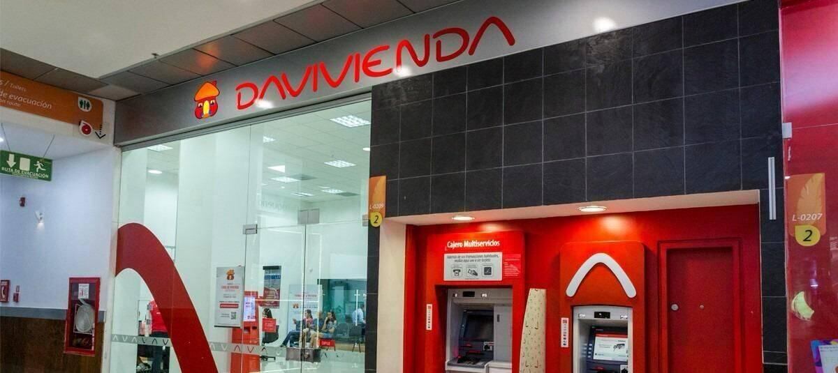 Vista frontal de una sucursal de Davivienda, con peatones transitando frente al edificio en una calle urbana.