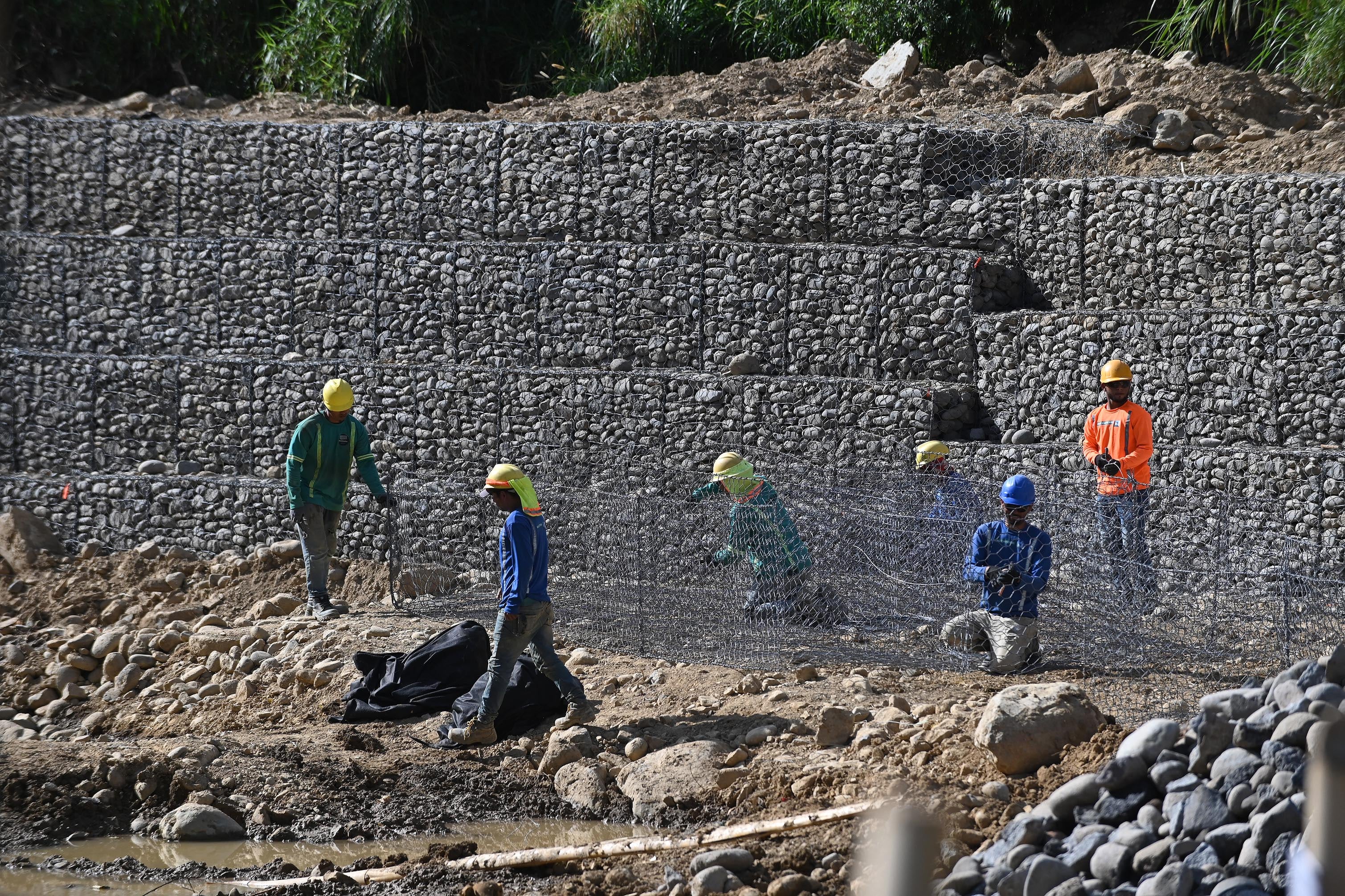 04 de abril del 2025. San Rafael Arriba de Desamparados. Río Cañas. 06:00 hrs. Maquinaria y personal de una empresa constructora privada realizan la construcción de varios muros de retención (gaviones) a lo largo del río Cañas al sur de la capital. La obra es financiada por el BCIE (Banco Centroamericano de Integración Económica) y gestionada por la Comisión Nacional de Emergencias. El proyecto beneficiaría a unas 24000 personas de comunidades como Calle Robles, San Bosco, Blanca Durán y La Granja que sufrieron serios daños con las lluvias del año anterior. Algunos vecinos del lugar externaron su molestia pues consideran que se refuerzan orillas del cauce del río pero se debilitan otras. En la foto: maquinaria pesada y personal de una constructora privada realizan las labores en el río Cañas. Foto: Albert Marín para la Nación.