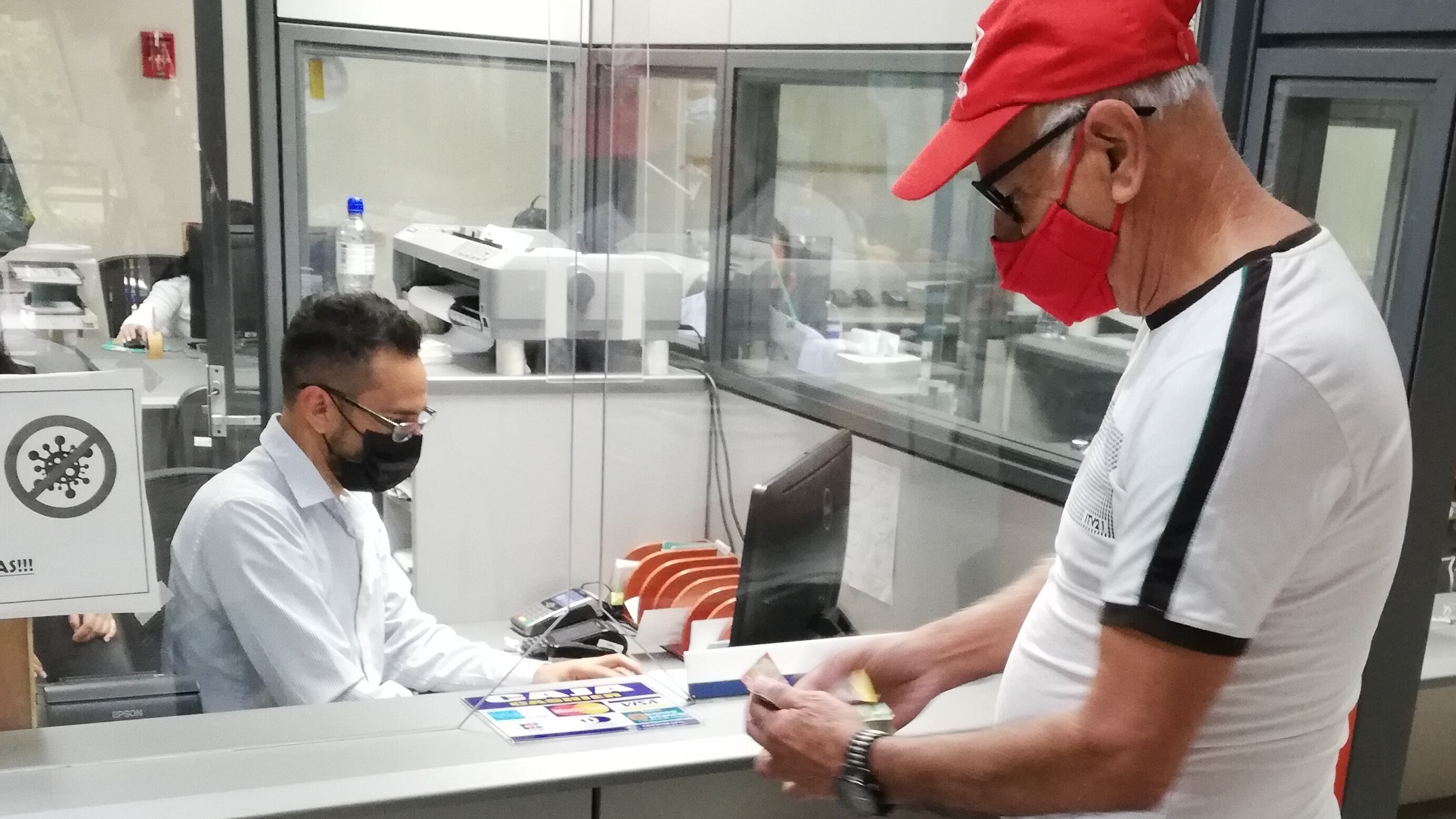 Don Carlos Chacón Alvarado, pensionado y de 73 años, cumplió por 13 años consecutivos su compromiso de ser el primer tico que paga el derecho de circulación 2022. En la foto el cajero del INS, Alejandro Molina, le recibe el pago del marchamo 2022 a don Carlos.