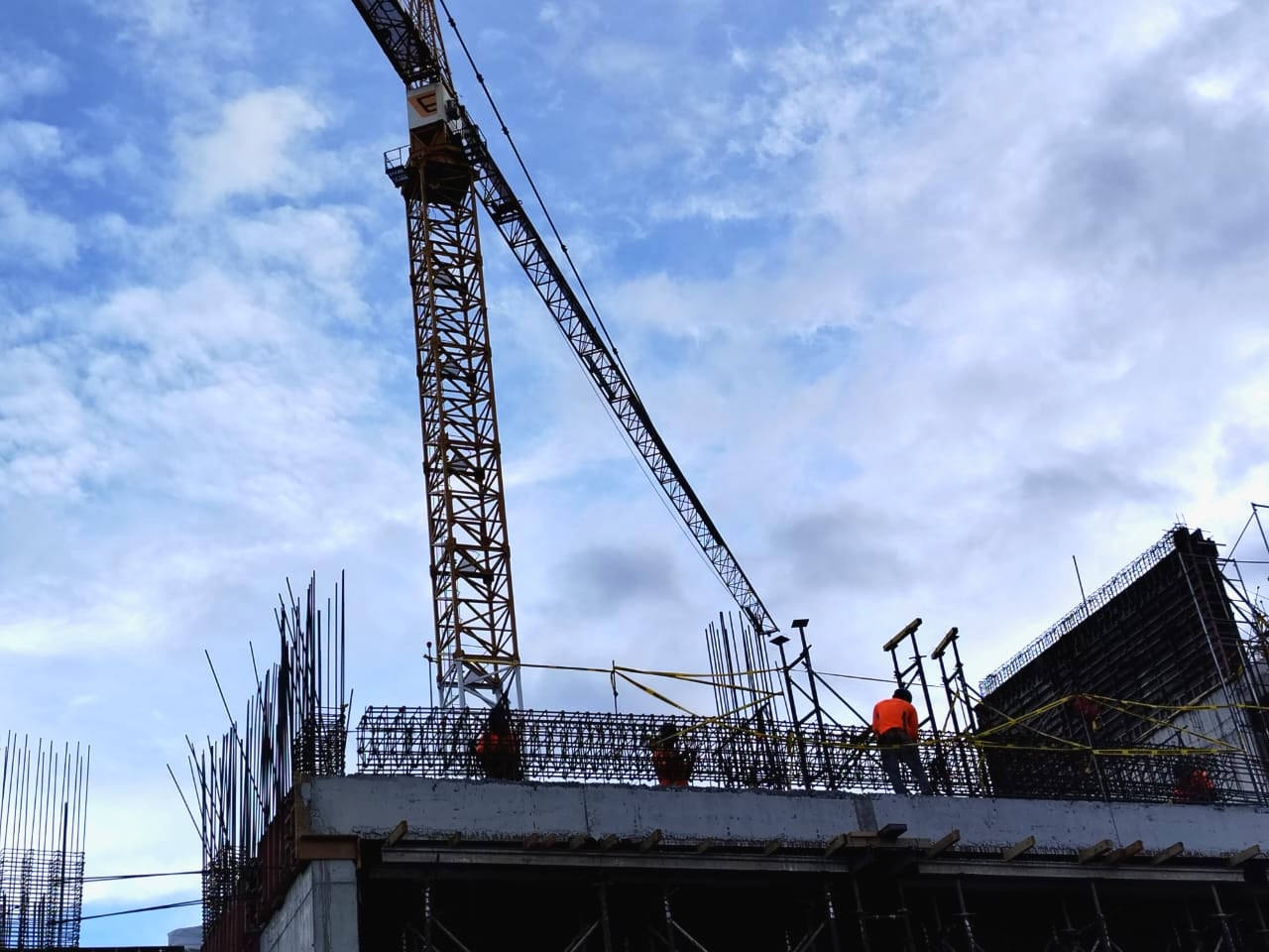 Obra en construcción con estructura metálica, trabajadores en altura y grúa torre, reflejo del contexto laboral en América Latina ante los desafíos económicos y tecnológicos proyectados para 2025.