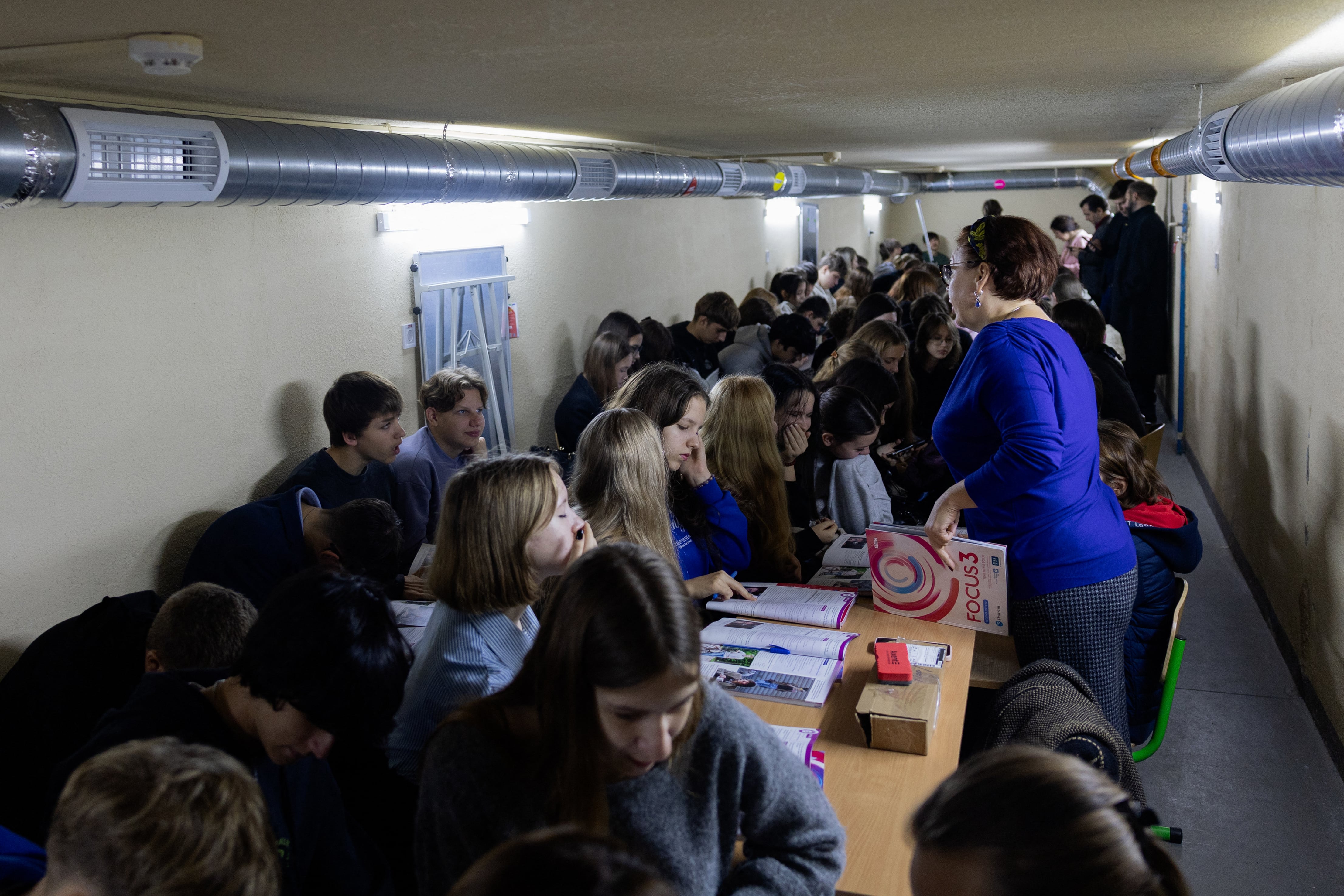 Orest, de 14 años, y sus compañeros de clase estudian en un refugio durante una alerta aérea en Kiev el 13 de octubre de 2026, en medio de la invasión rusa de Ucrania. Anastasiia, de 44 años, tiene tres hijos, trabaja en un hospital y dispone de poco tiempo para sí misma. Desde finales del verano, Moscú le ha «añadido algunas tareas extra», comenta con una chispa de picardía que apenas logra ocultar su fatiga. Las alertas aéreas y las explosiones interrumpen sus noches y marcan el ritmo de sus días, a medida que Rusia intensifica sus ataques con drones propulsados por motores a reacción, los cuales han causado la muerte de más de 190 personas en Kiev desde enero de 2026, según las autoridades municipales. Entre llevar a su hijo de 14 años a la escuela y estar pendiente de su hijo mayor, de 19, Anastasiia organiza ahora su rutina en función del riesgo de ataques. (Foto de Tetiana DZHAFAROVA / AFP)