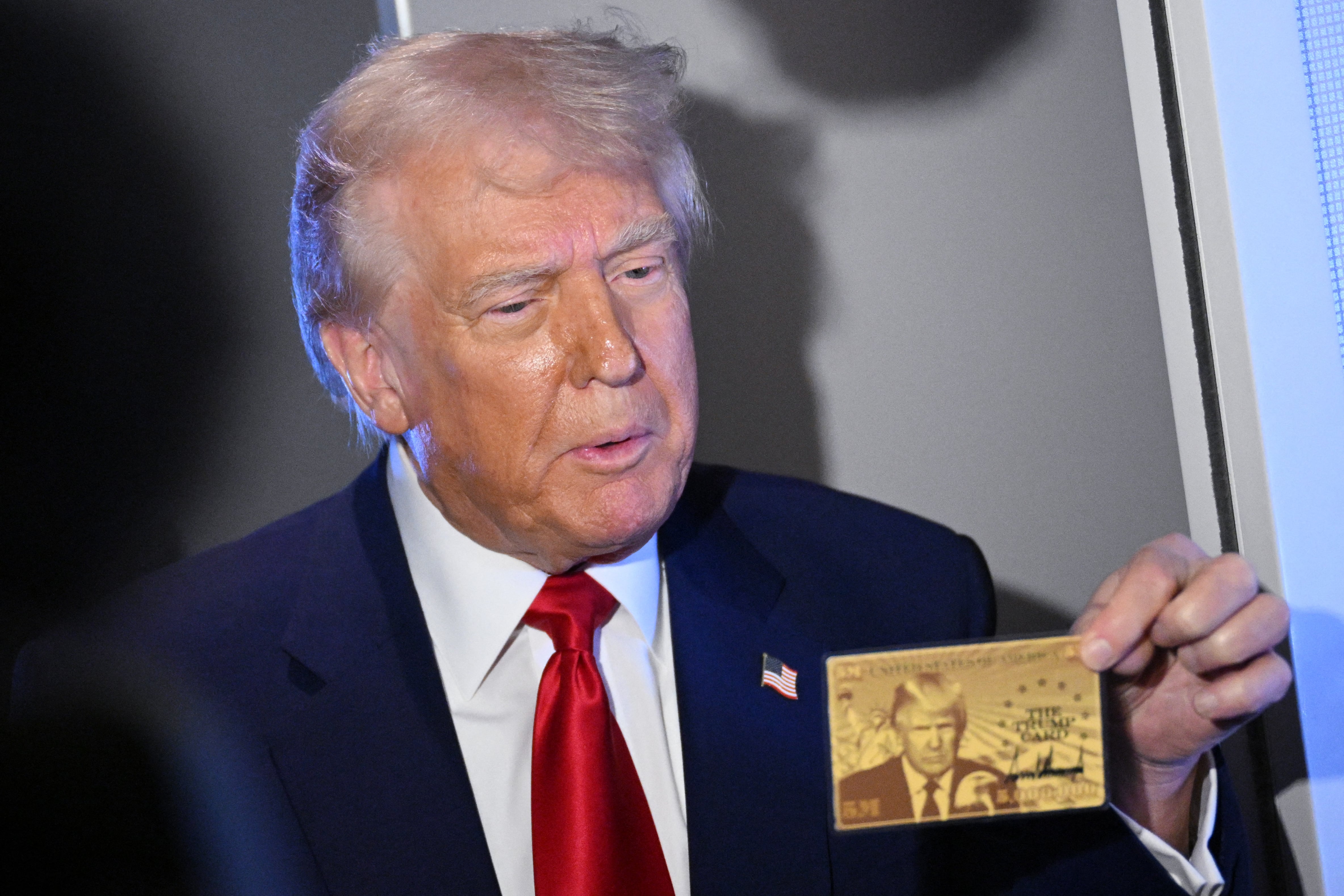 El presidente de los Estados Unidos, Donald Trump, sostiene la Tarjeta o Visa Dorada de 5 millones de dólares mientras habla con los periodistas durante un vuelo a bordo del Air Force One, en ruta a Miami, Florida, el 3 de abril de 2025.
