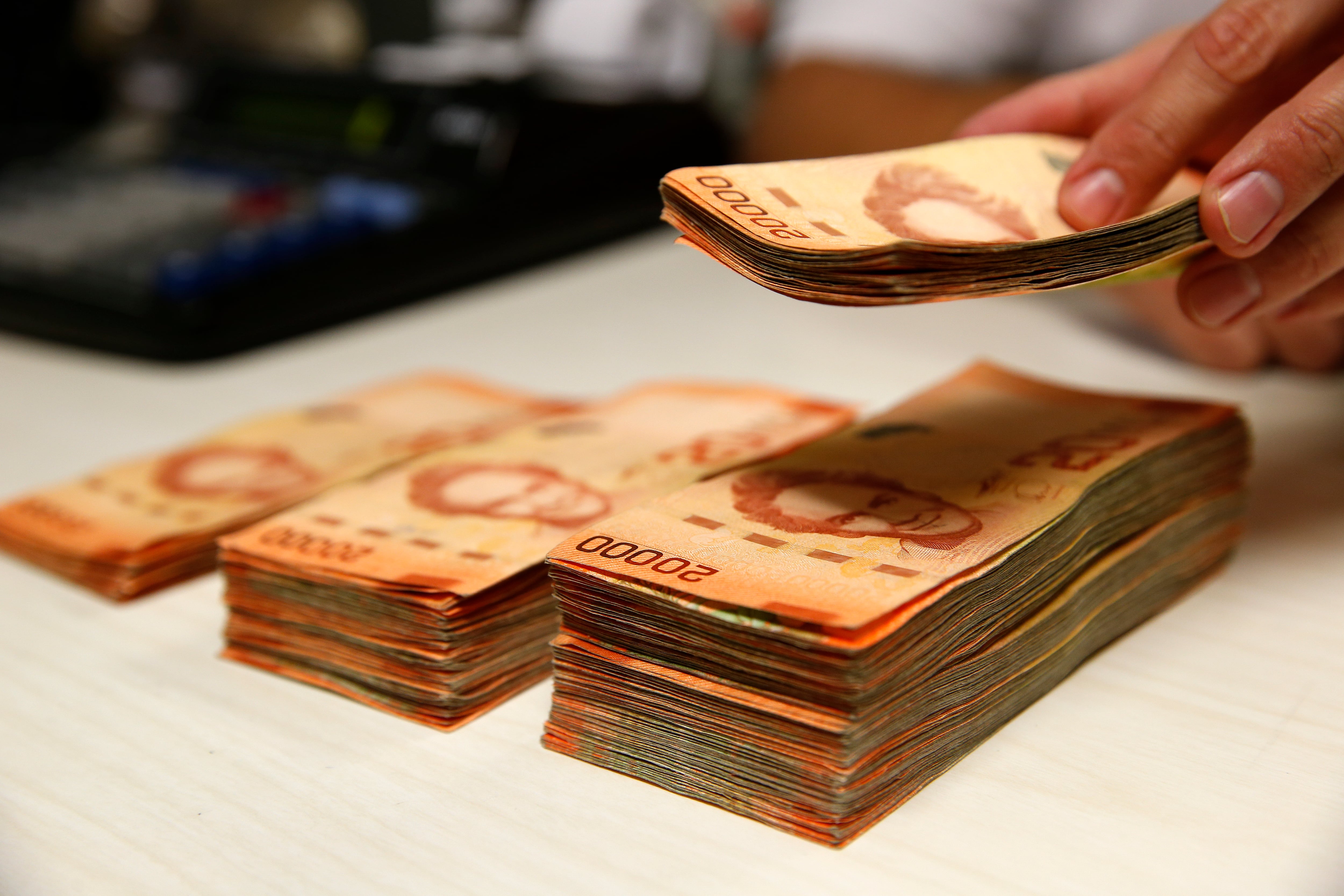 Persona cuenta billetes de ¢20.000 en una entidad bancaria.