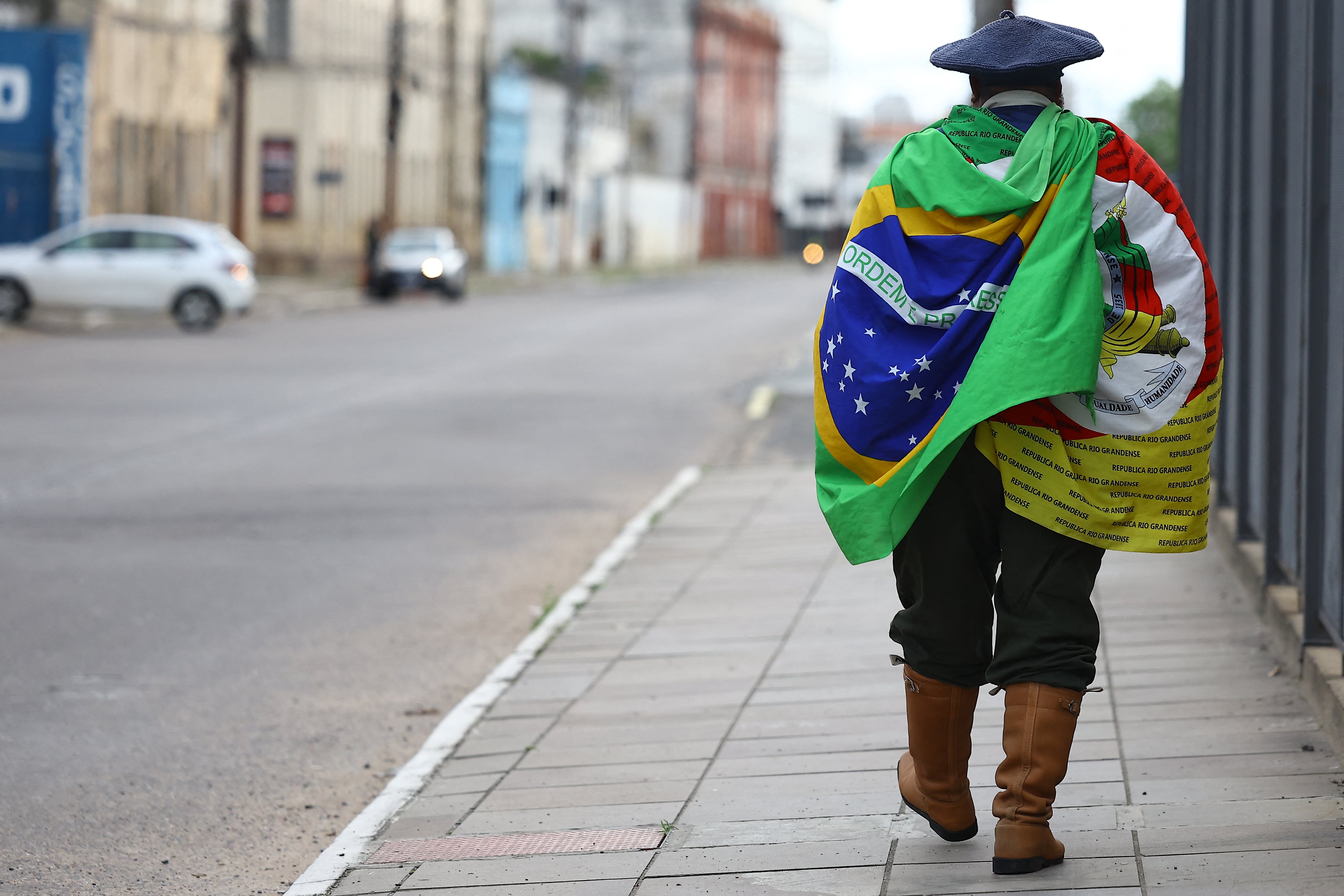 A supporter of Brazil's right-wing senator and presidential candidate Flavio Bolsonaro of the Liberal Party (PL) walks along a street after polls closed in the general election in Porto Alegre, Brazil, on October 4, 2026. Brazilians waited anxiously for the results of a tight election race between President Luiz Inacio Lula and Flavio Bolsonaro that will determine if the Latin American powerhouse joins a regional swing to the right championed by US President Donald Trump. (Photo by SILVIO AVILA / AFP)