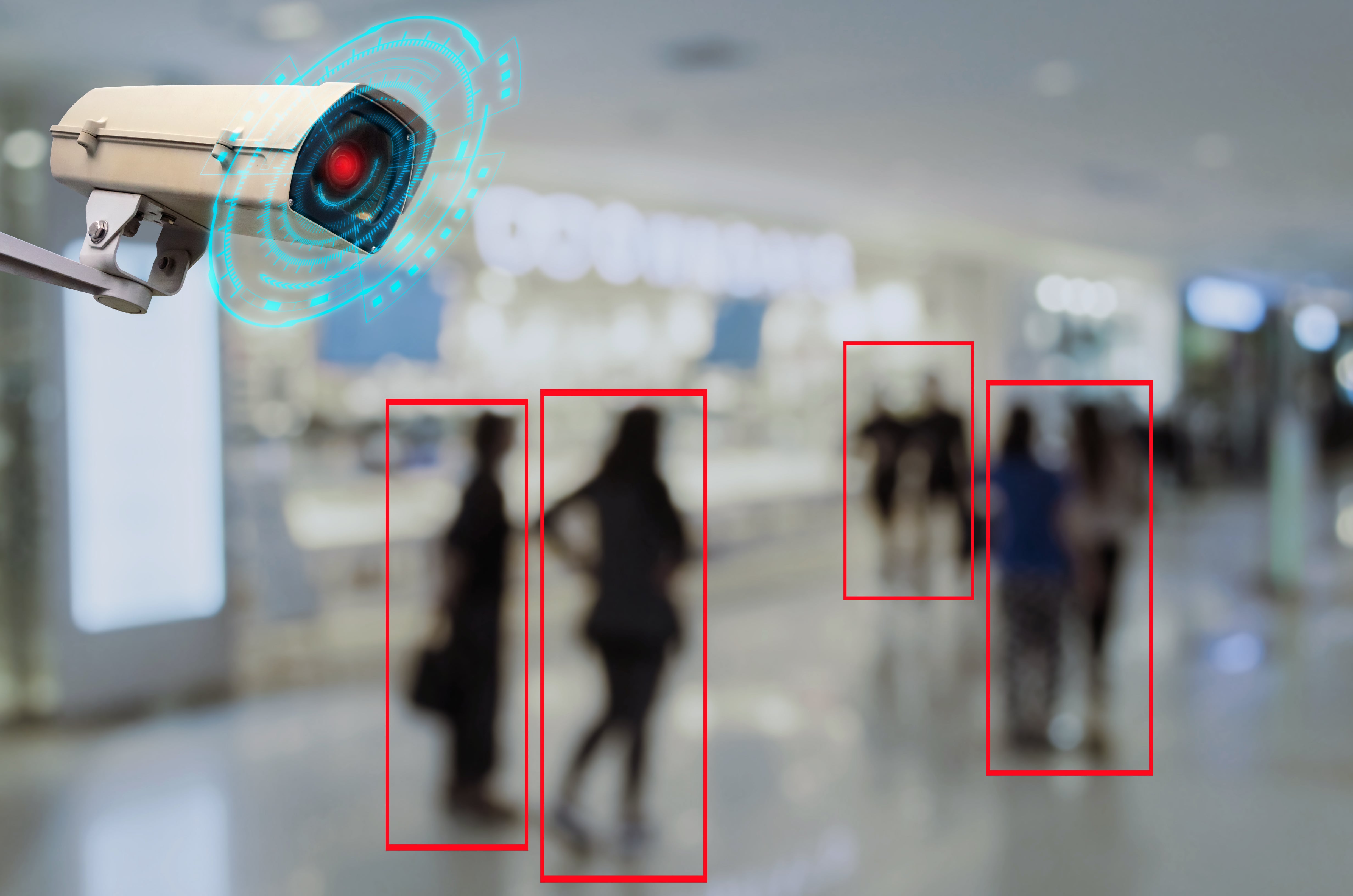 En la imagen personas borrosas y una cámara de seguridad