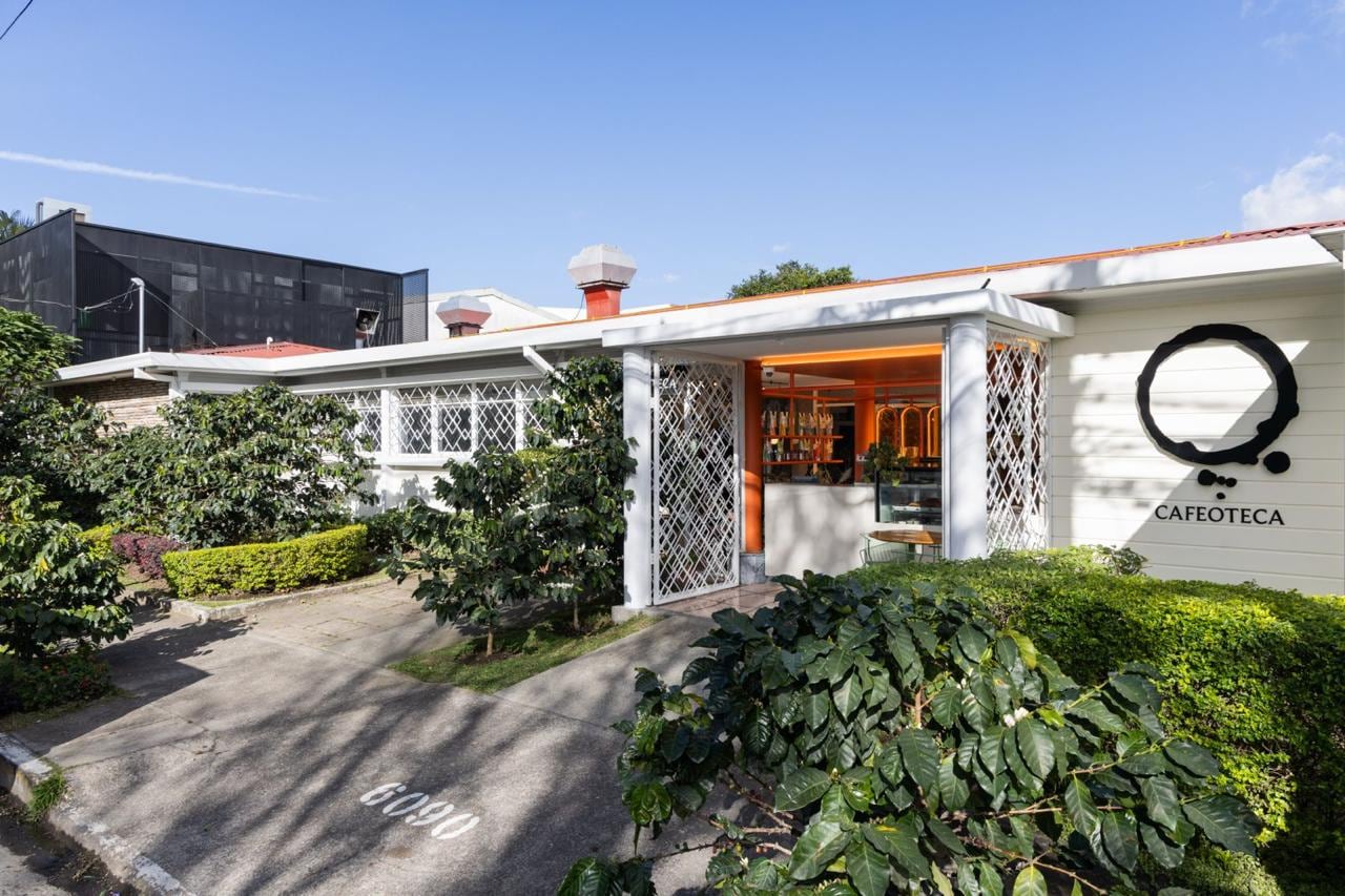 Fachada de una cafetería de San José, Costa Rica con paredes blancas y jardín