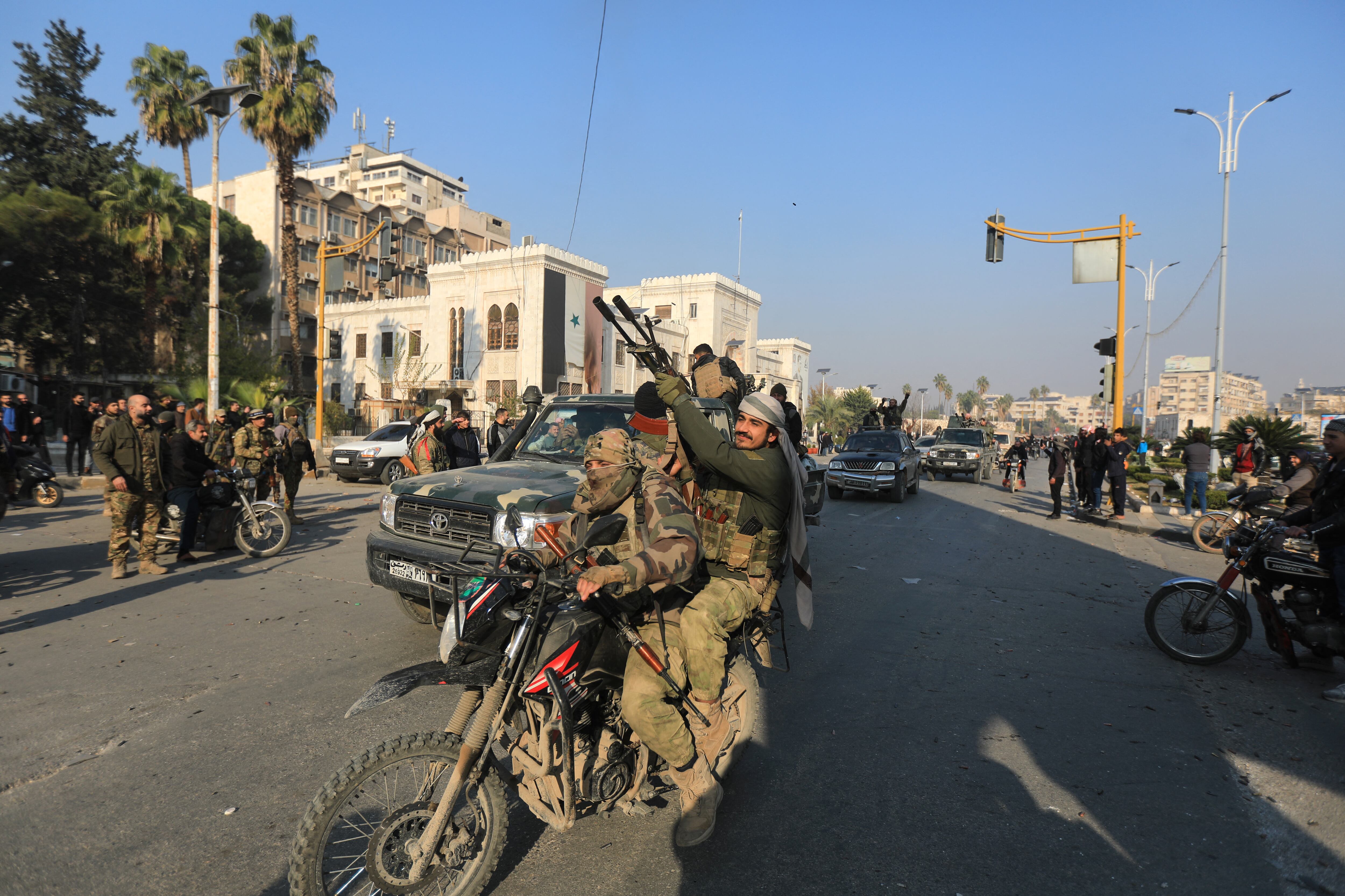Combatientes antigubernamentales desfilan por las calles de Hama tras capturar la ciudad durante la ofensiva rebelde en Siria en diciembre de 2024.