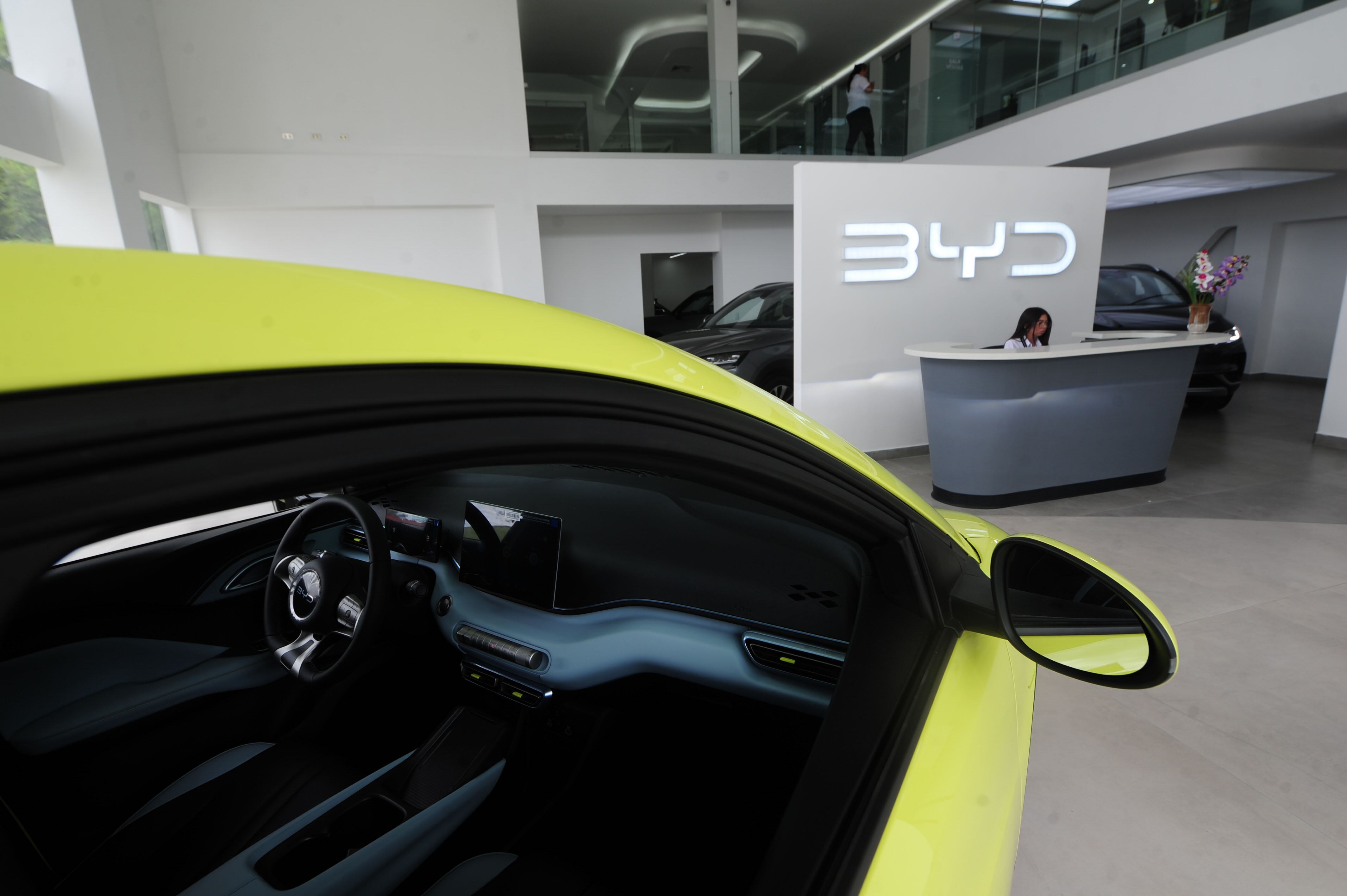 Interior de la nueva sala de exposición de Grupo Cori Motors en Tres Ríos, destacando un modelo eléctrico amarillo y la recepción moderna del showroom.