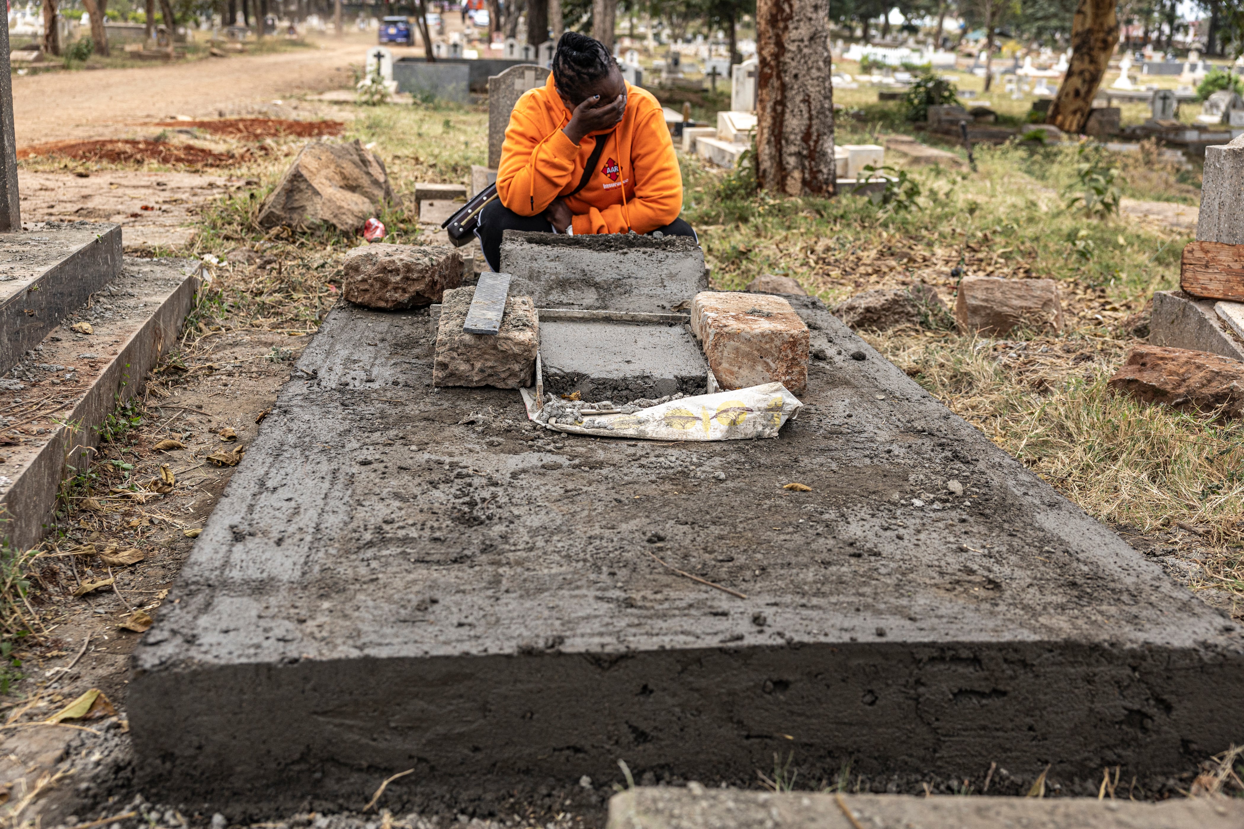 Catherine llora junto a la tumba recién cementada de su amiga Judy, una trabajadora sexual keniana VIH positiva que murió de una enfermedad relacionada con el SIDA, en el cementerio Langata de Nairobi el 8 de septiembre de 2026.
Bajo un bloque de hormigón anónimo en un cementerio de Nairobi se encuentran los restos de Judy, una trabajadora sexual keniana seropositiva, que murió pocas horas antes de su reunión con la AFP el mes pasado, una víctima más de los recortes de ayuda estadounidenses.
La AFP ha confirmado la muerte de al menos 24 trabajadoras sexuales seropositivas en Kenia que, como Judy, gozaban de buena salud hasta que Estados Unidos redujo drásticamente la ayuda a principios de 2025, según personal sanitario de primera línea.
Es probable que el número real de muertes sea mucho mayor, y las ONG dicen que ya hay un enorme aumento en las infecciones por VIH entre los trabajadores sexuales que probablemente provocará un aumento "catastrófico" de los casos entre la población general.