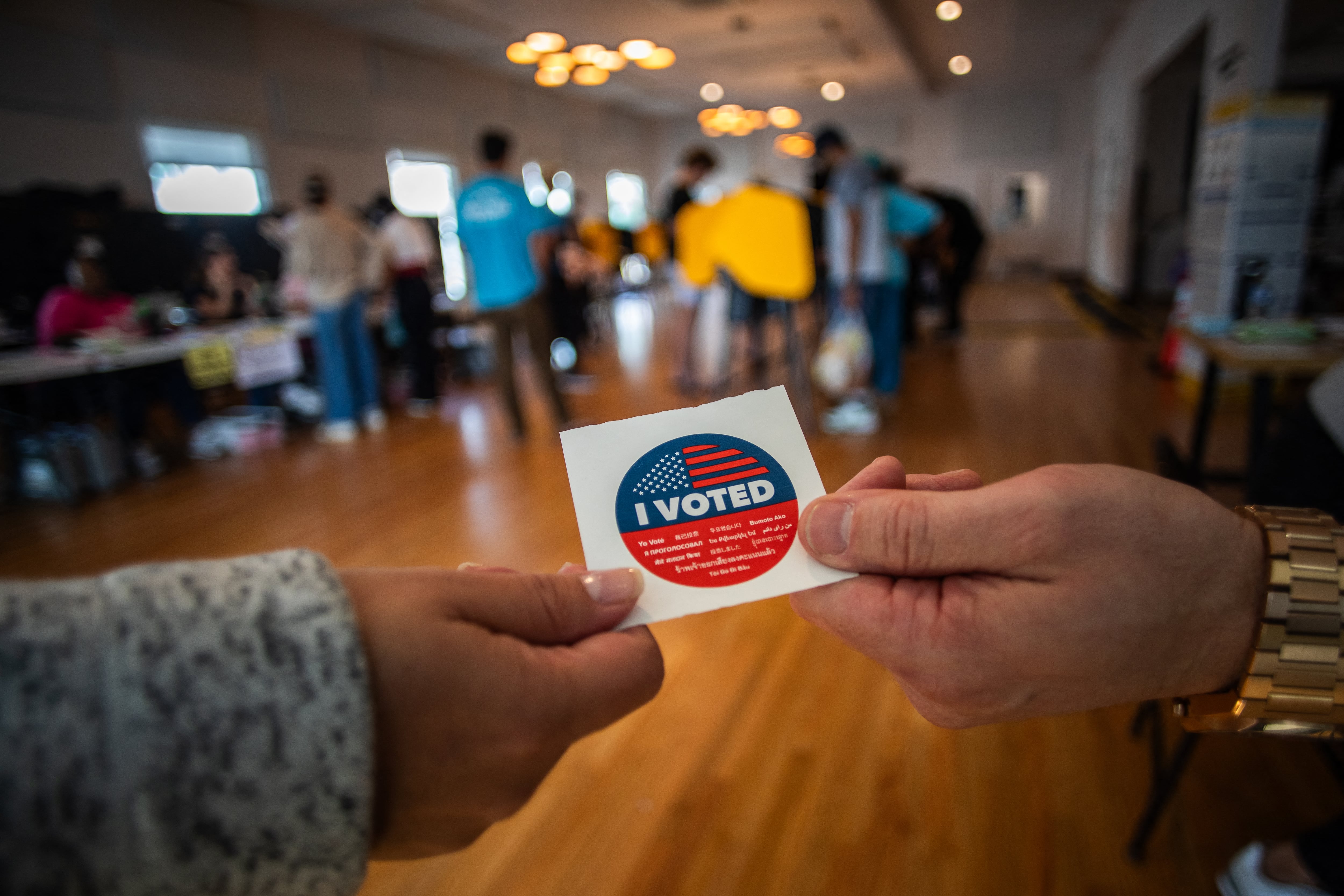 Un hombre recibe una calcomanía con la leyenda 'Yo voté' después de votar en el centro de votación Neptunian Womans Club-Manhattan Beach el 5 de noviembre de 2024 en Los Ángeles, California.