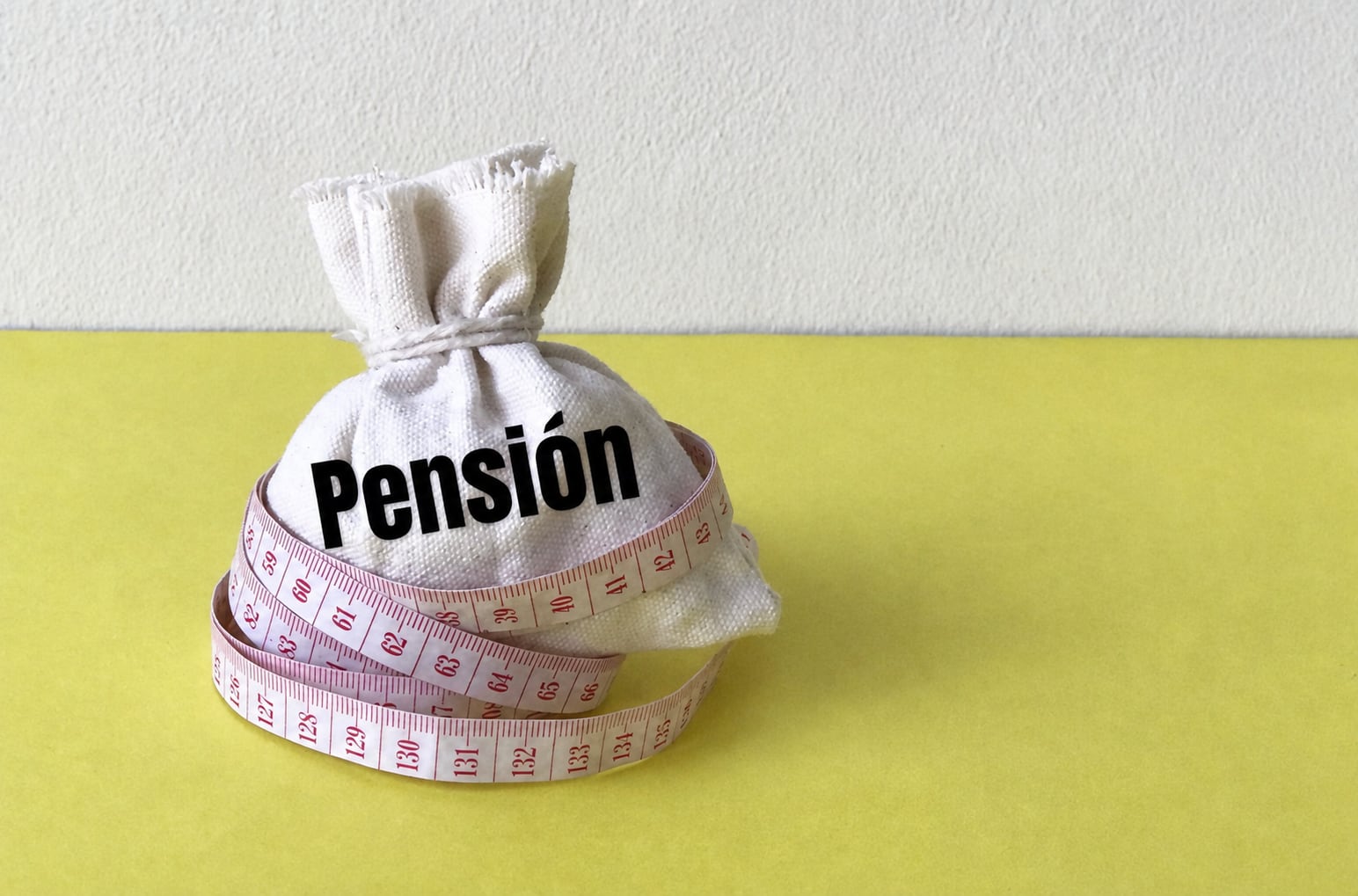 en la imagen una bolsa de dinero que dice "pensión" con una cinta métrica alrededor