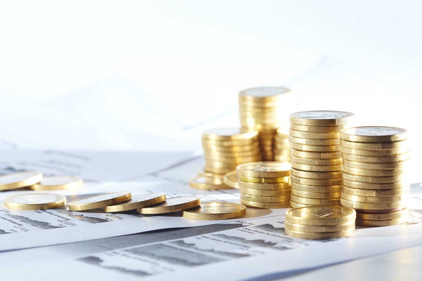 Pilas de monedas de oro sobre documentos financieros, simbolizando el ajuste del Índice de Salarios Mínimos (ISM) publicado por el Banco Central de Costa Rica en febrero de 2024.
