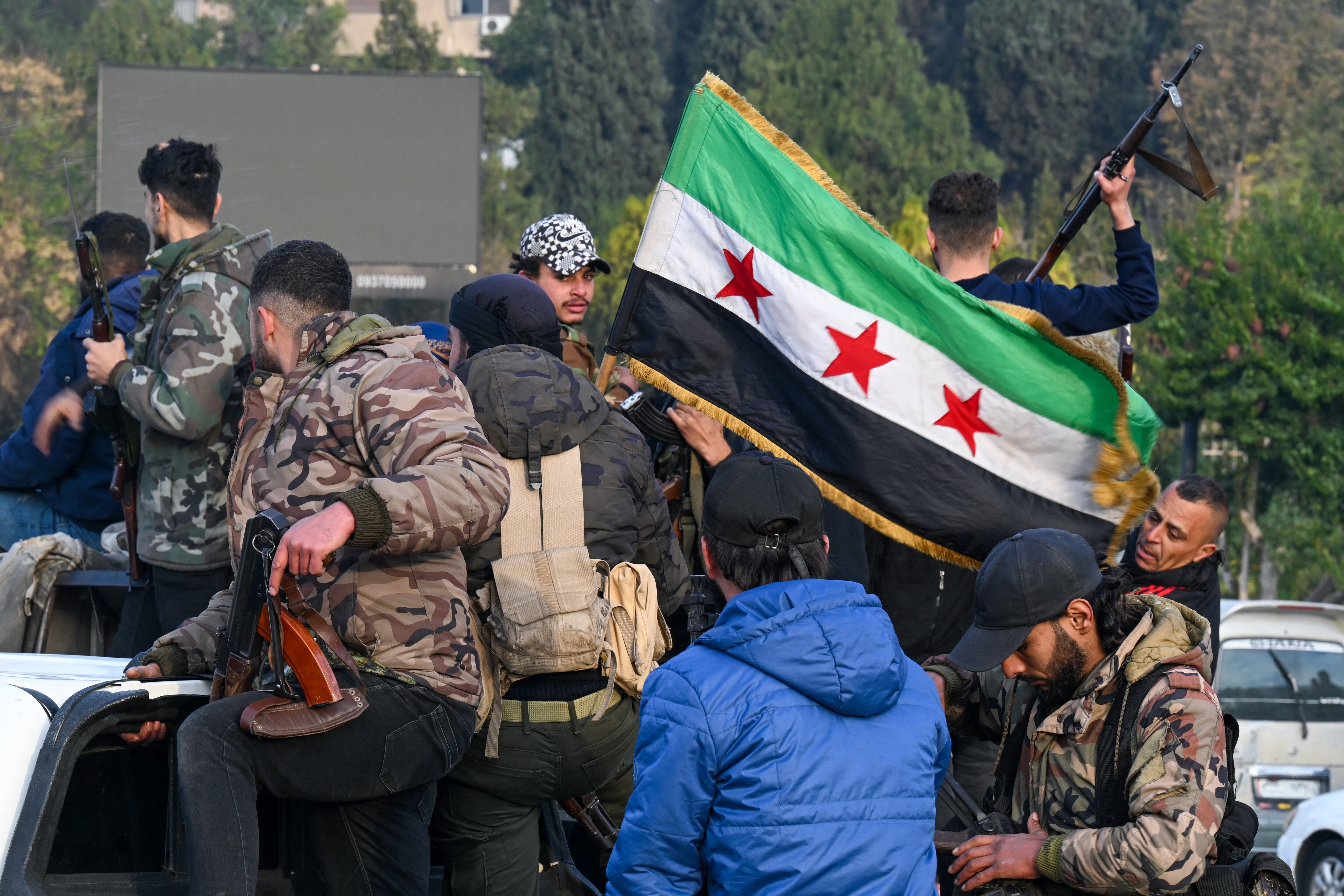 Rebeldes sirios con armas y la bandera de la revolución tras tomar Damasco.