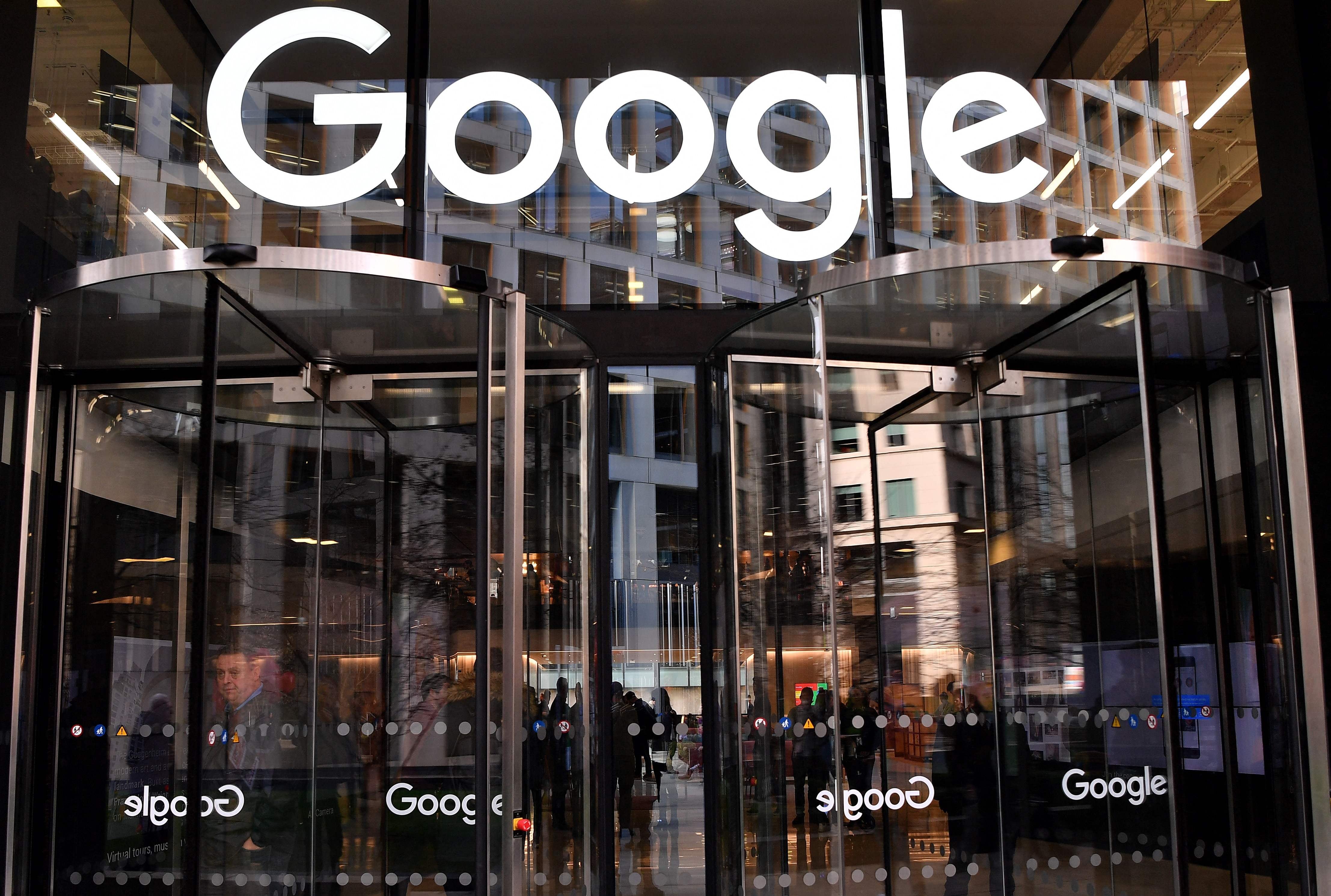 Entrada principal del edificio de Google con puertas giratorias y el logo de la empresa, en el contexto de una investigación antimonopolio iniciada por China.