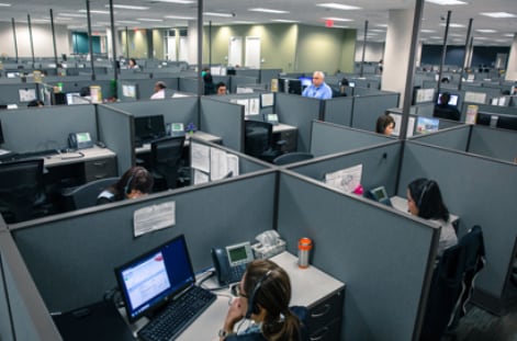 Oficinas de CyraCom con personal trabajando en cubículos. La compañía estadounidense de traducción e interpretación cerrará sus operaciones en el país.