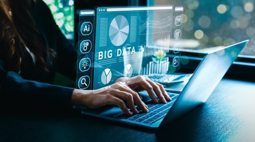 Manos trabajando en una computadora portátil con gráficos digitales de big data e inteligencia artificial, representando el uso de tecnología contra la corrupción.